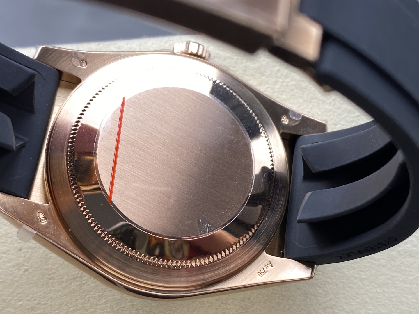 Caseback view of a rose gold Rolex replica watch with black rubber strap and protective film