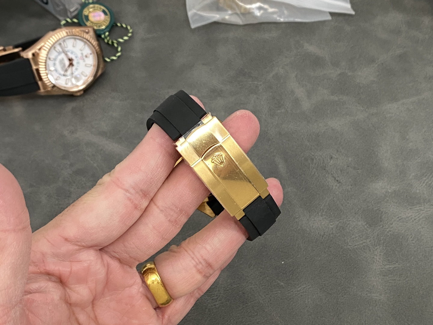 Detailed view of gold Rolex-style clasp with engraved crown on black rubber strap