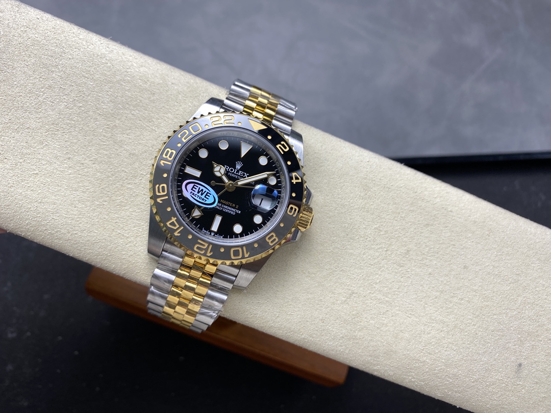 Premium two-tone Rolex GMT-Master II replica with black ceramic bezel and gold accents resting on a cream watch display cushion