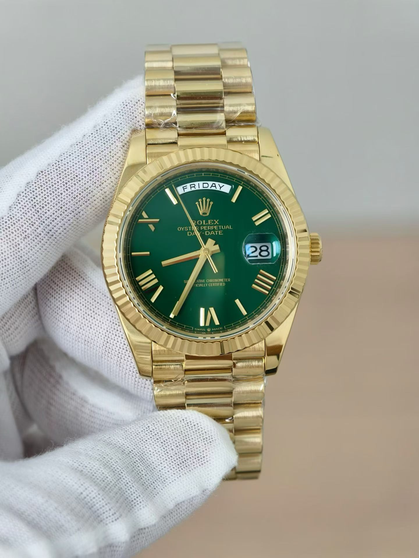 Elegant gold Rolex Oyster Perpetual Day-Date replica held in gloved hand showcasing the full watch with green sunburst dial