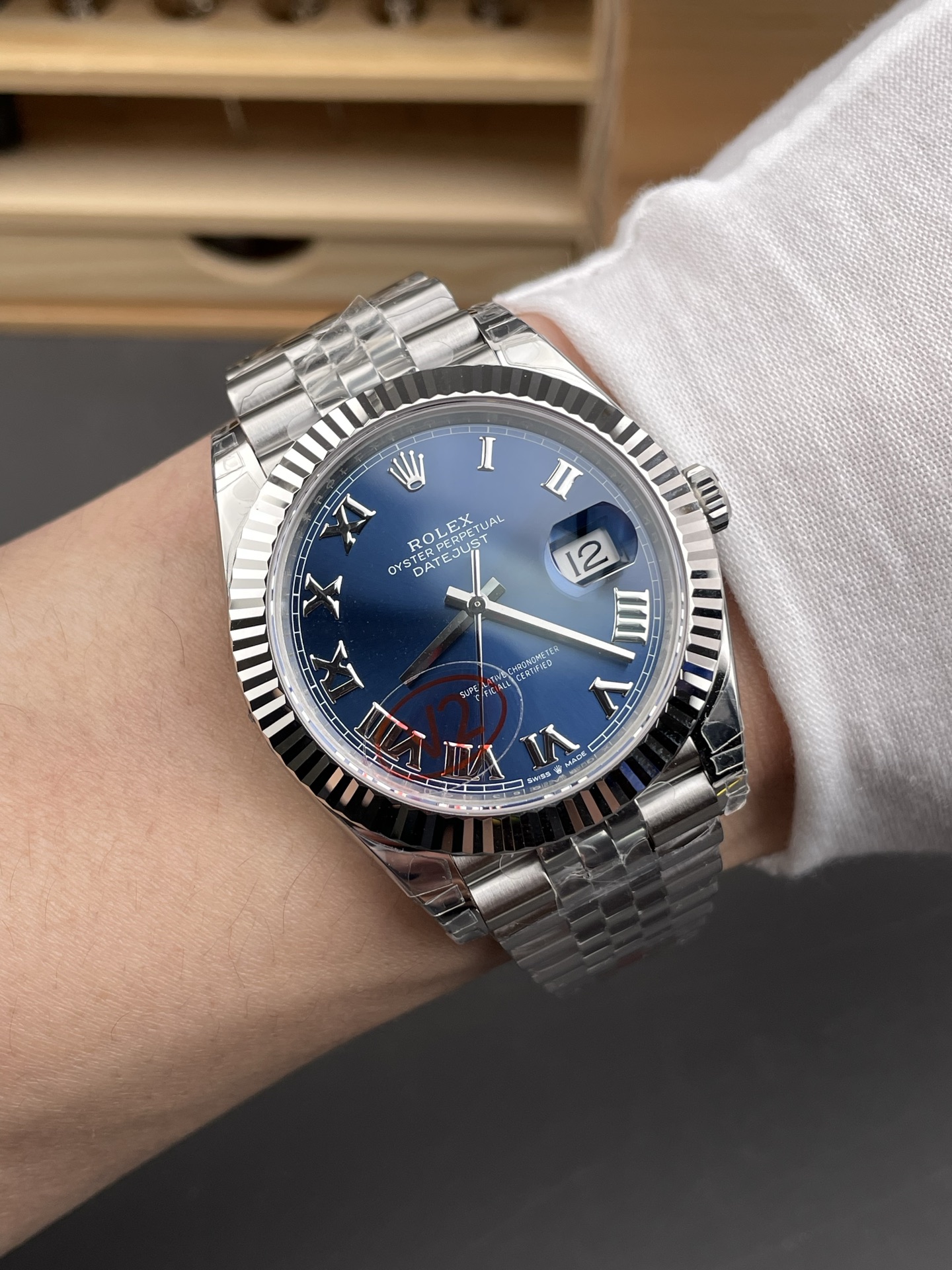 Rolex Datejust replica on wrist with blue dial, fluted bezel, and Jubilee bracelet