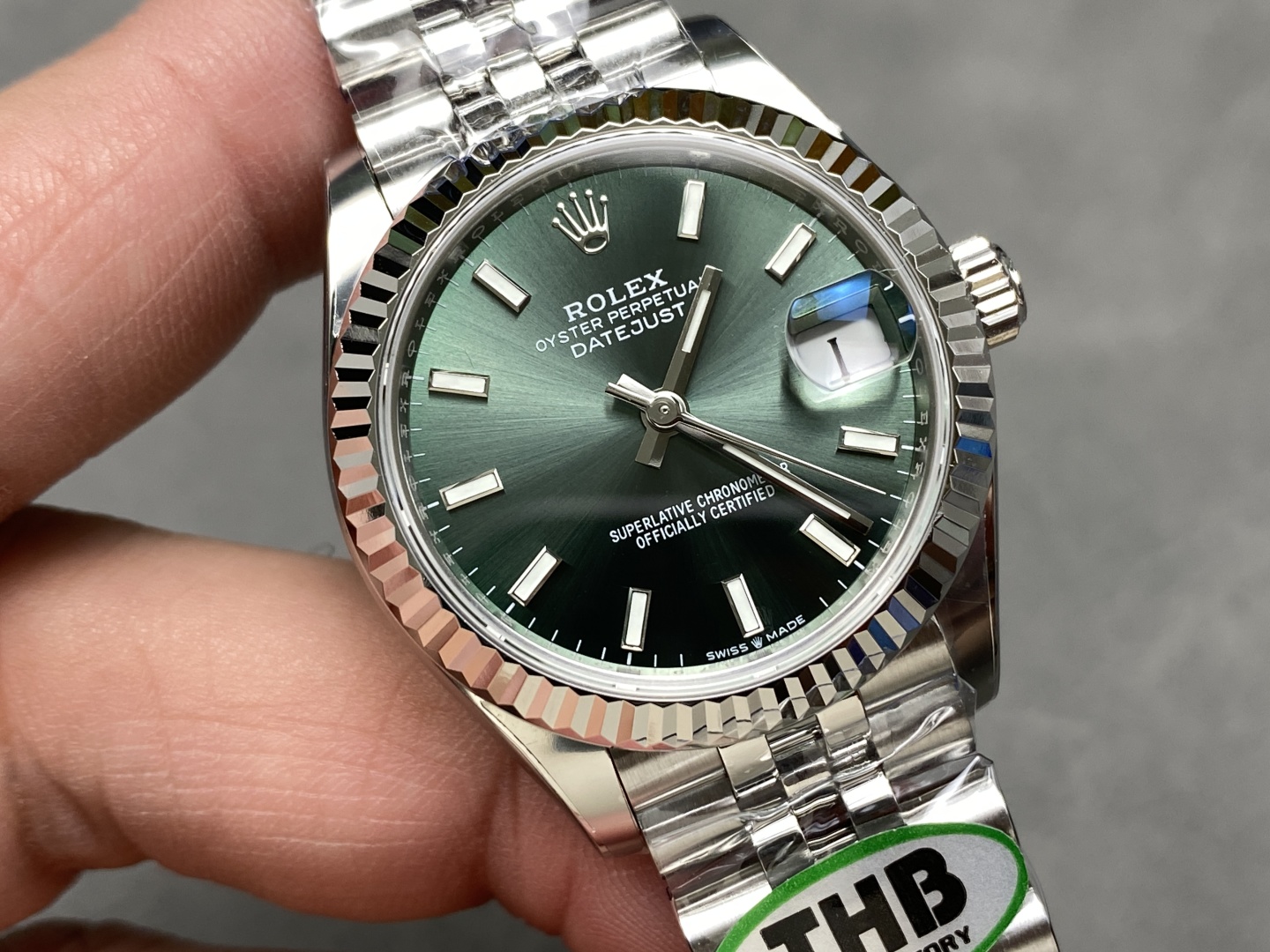 macro close-up of olive green dial with date window and white indices