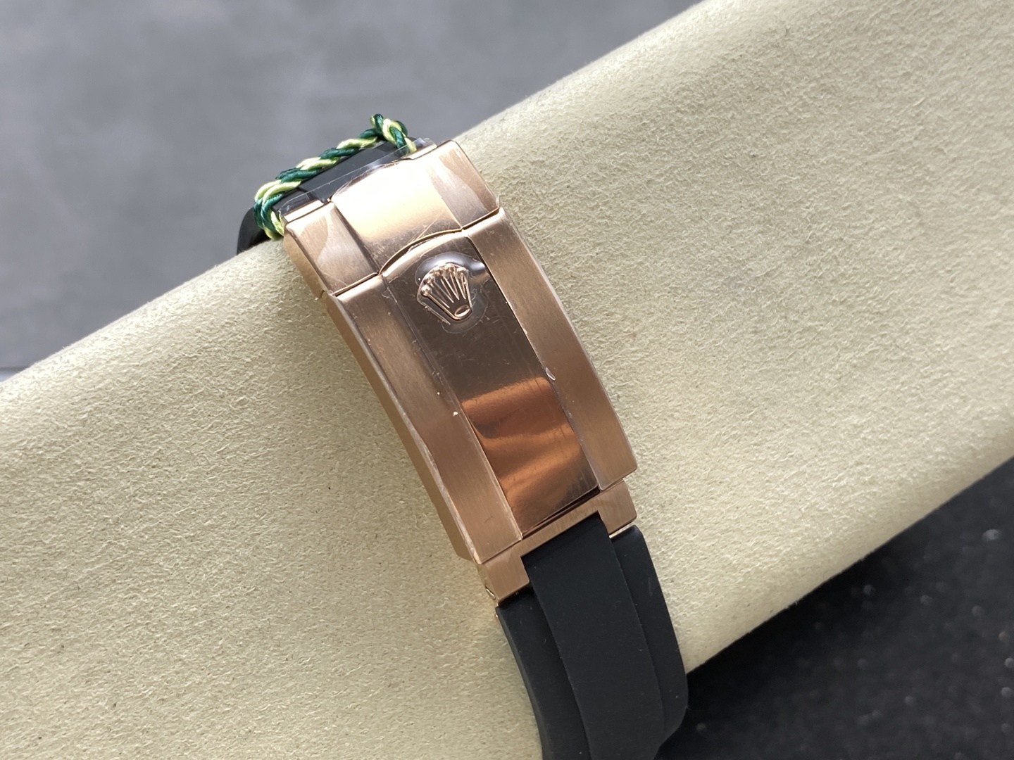 Rose gold Rolex replica clasp and black rubber strap on a cream watch display roll