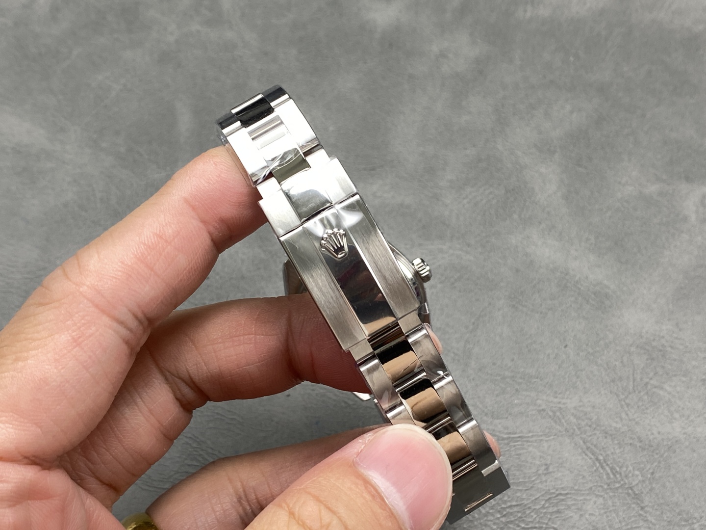 Close-up of the polished and brushed stainless steel Oyster bracelet on the Rolex replica, highlighting the engraved crown logo on the clasp and precise link construction
