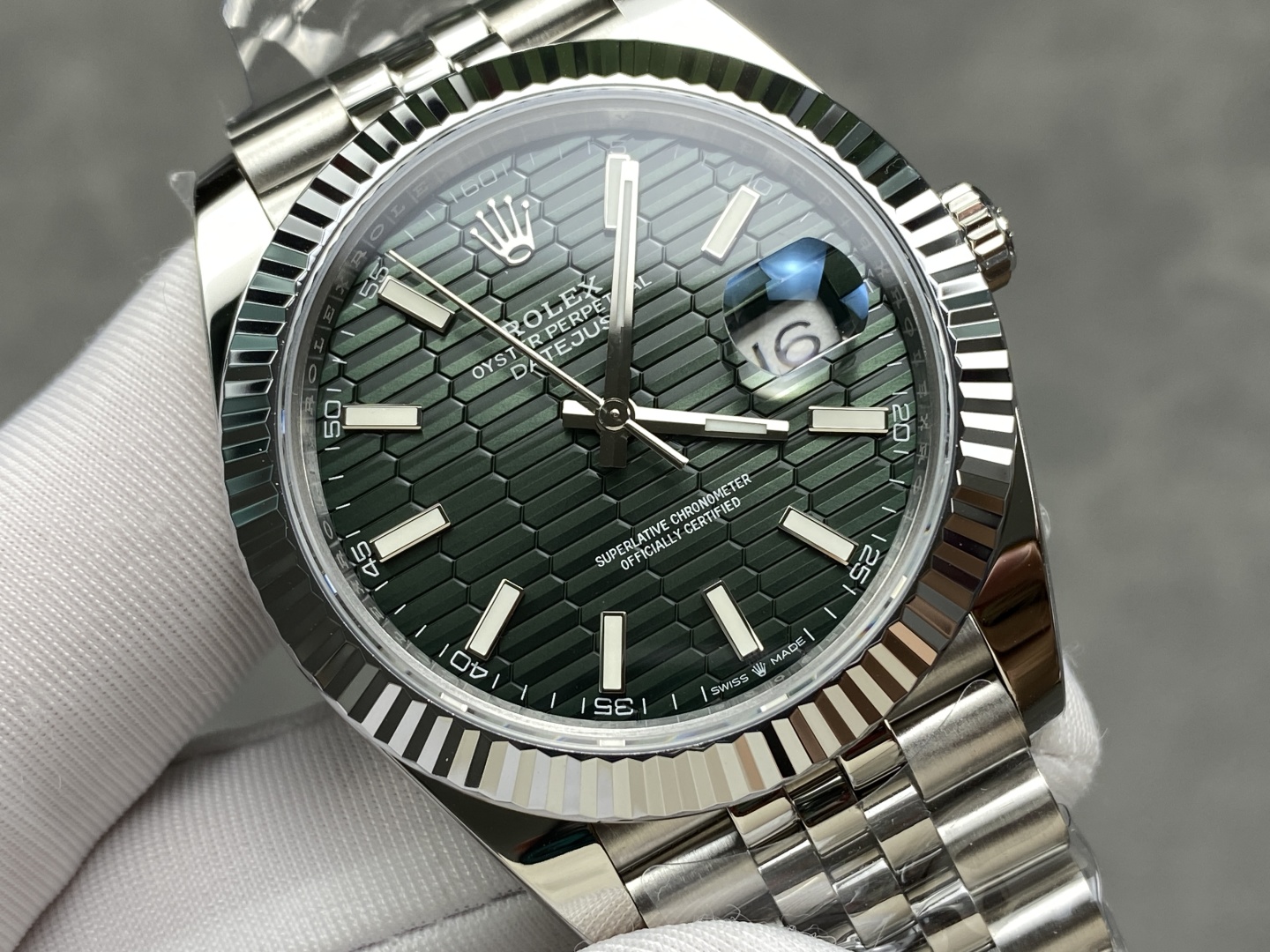 Close-up of the green motif dial and date window on a replica Rolex