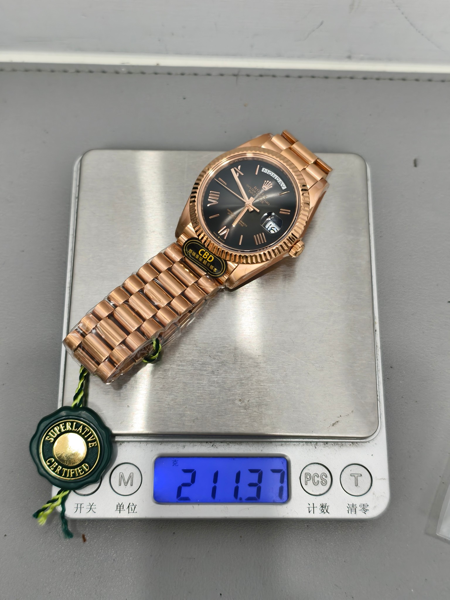 The rose gold replica Rolex Day-Date on a digital scale displaying 211.37 grams confirming original weight