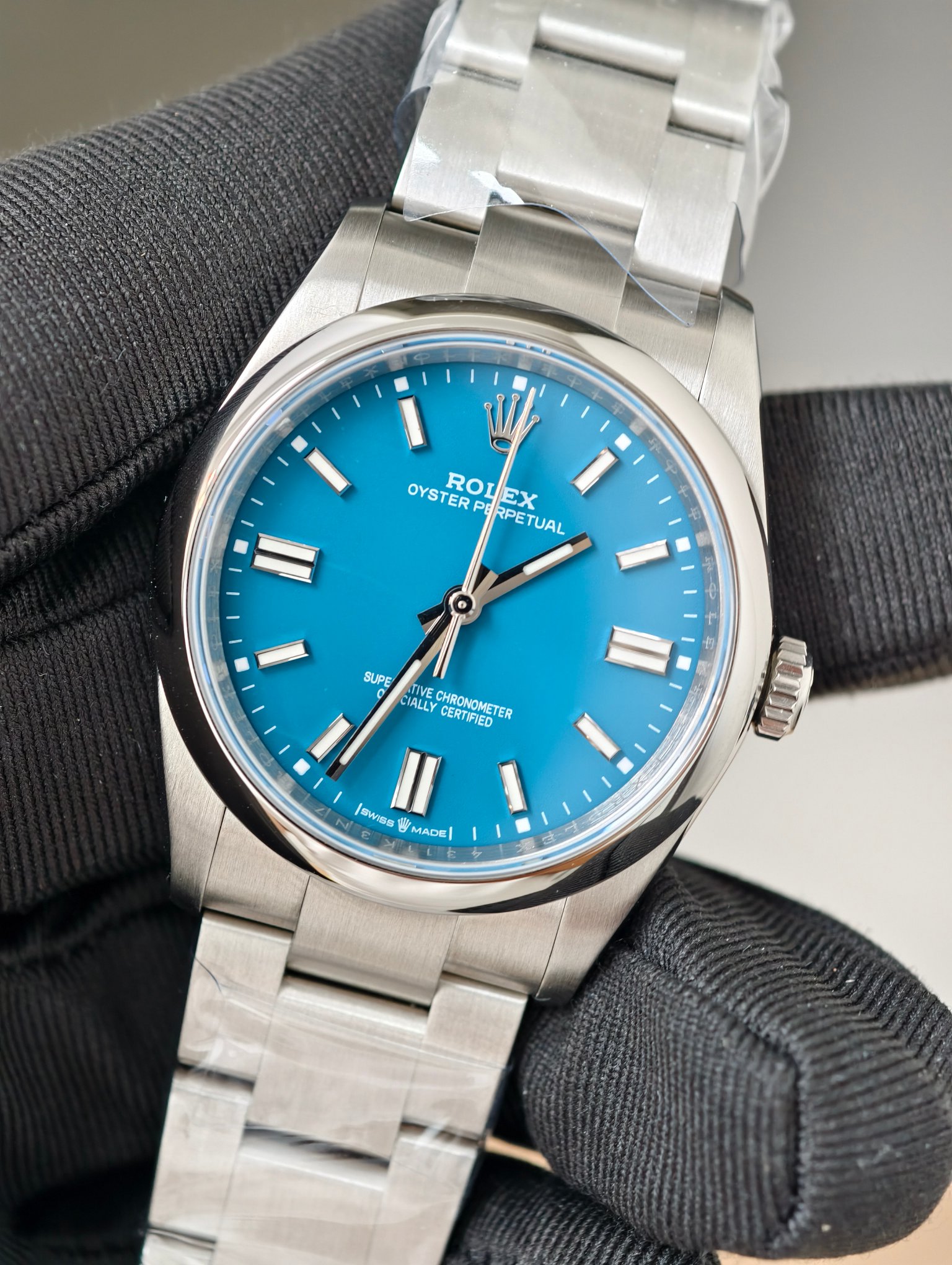 Close-up of Rolex Oyster Perpetual blue dial with ROLEX and OYSTER PERPETUAL text, silver hands, and superlative chronometer certification