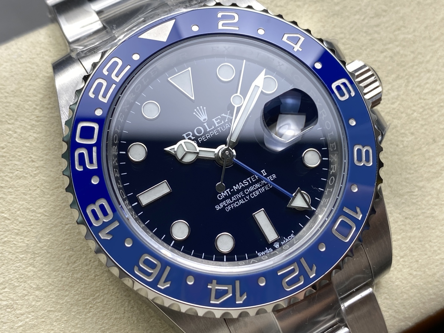 Hochwertige gefälschte Rolex GMT-Master II mit 3285 Uhrwerk und ikonischem Batman Bezel auf cremefarbenem Kissen