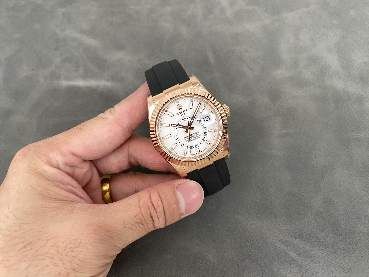Rolex Sky-Dweller replica held showing the 24-hour subdial and date complication in action