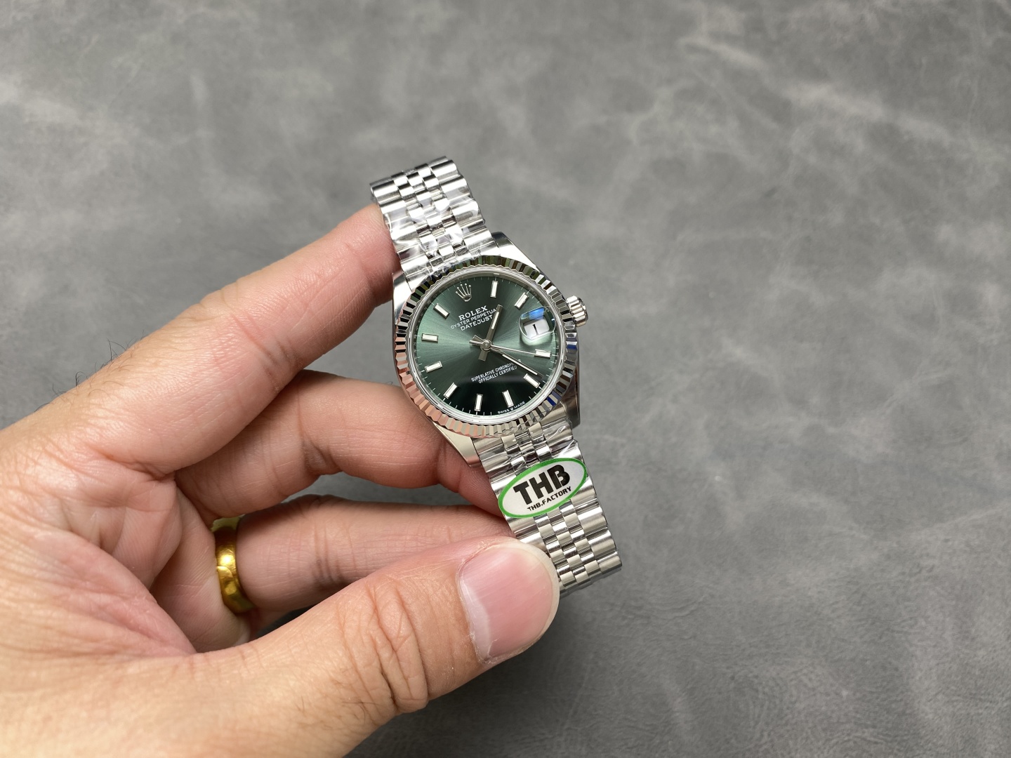 1:1 clone watch held in hand showing green dial and jubilee bracelet