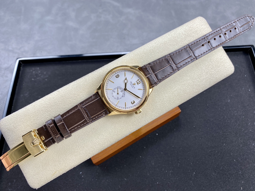 Close-up of a premium replica Rolex watch with a yellow gold case, white dial with Arabic numerals, and brown alligator leather strap on a cream display tray.