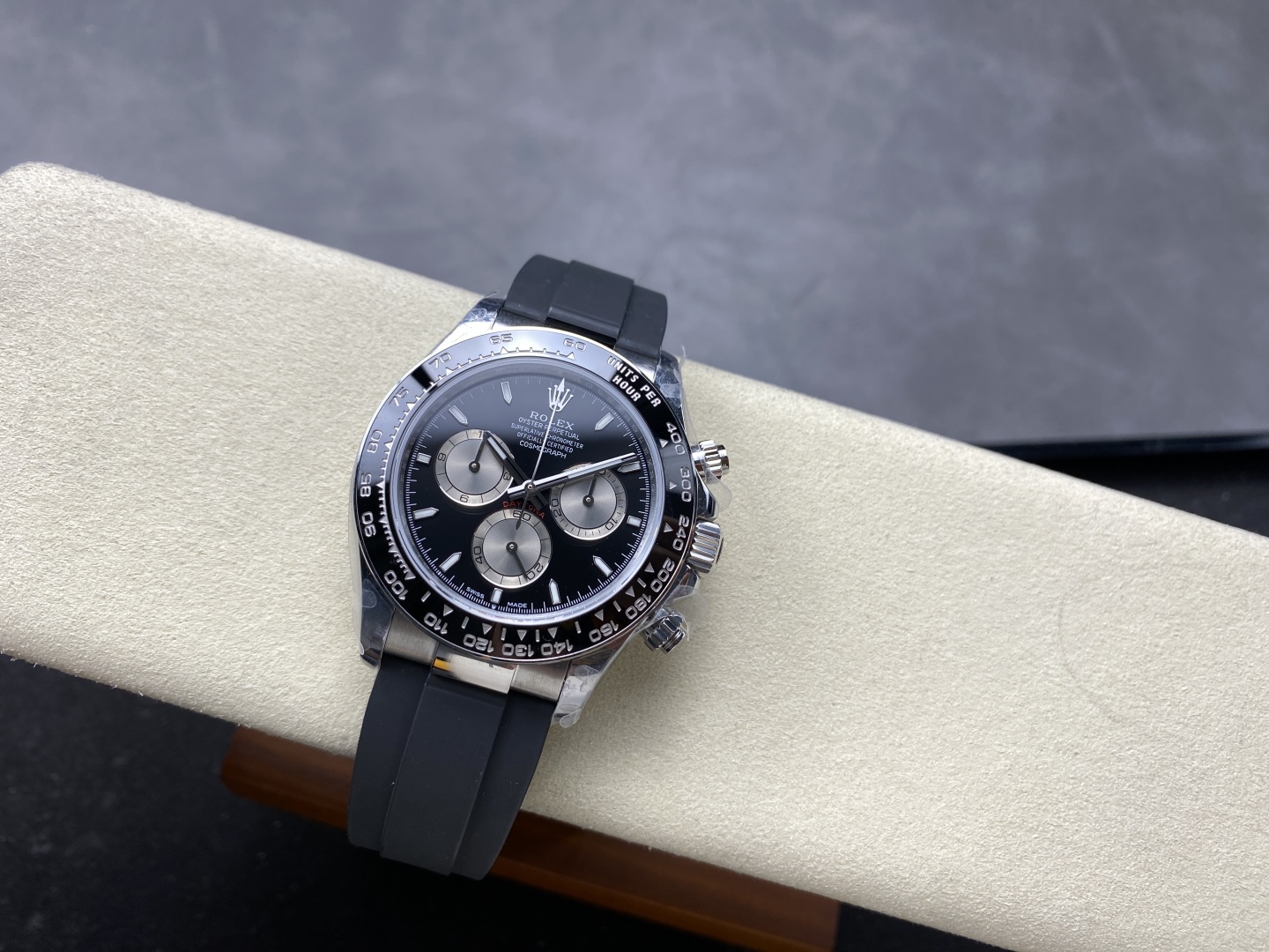 Black dial Rolex Daytona replica with rubber strap on a beige watch pad