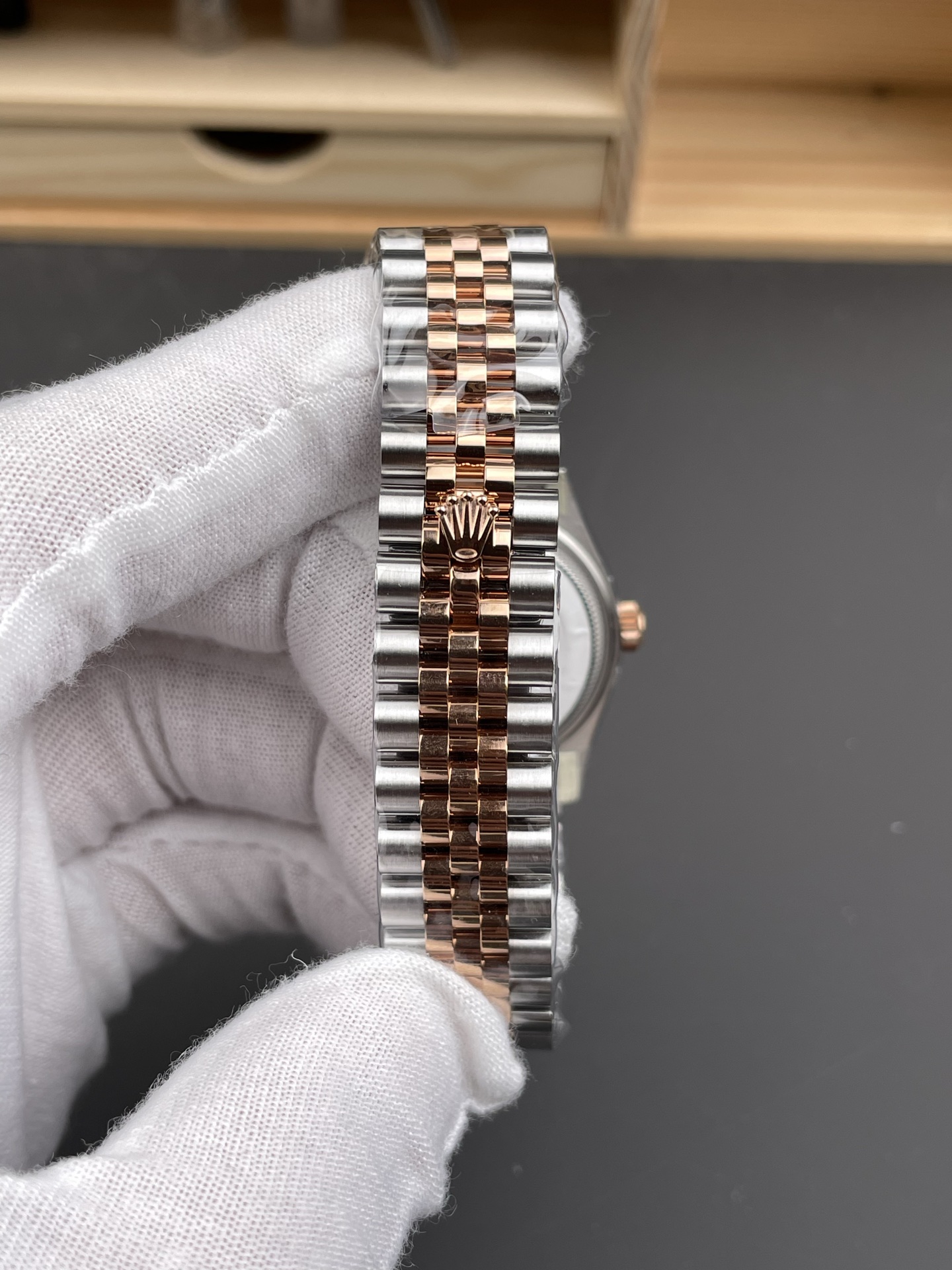 Detailed view of two-tone Oyster bracelet with rose gold center links and hidden folding clasp engraved with Rolex crown on replica watch