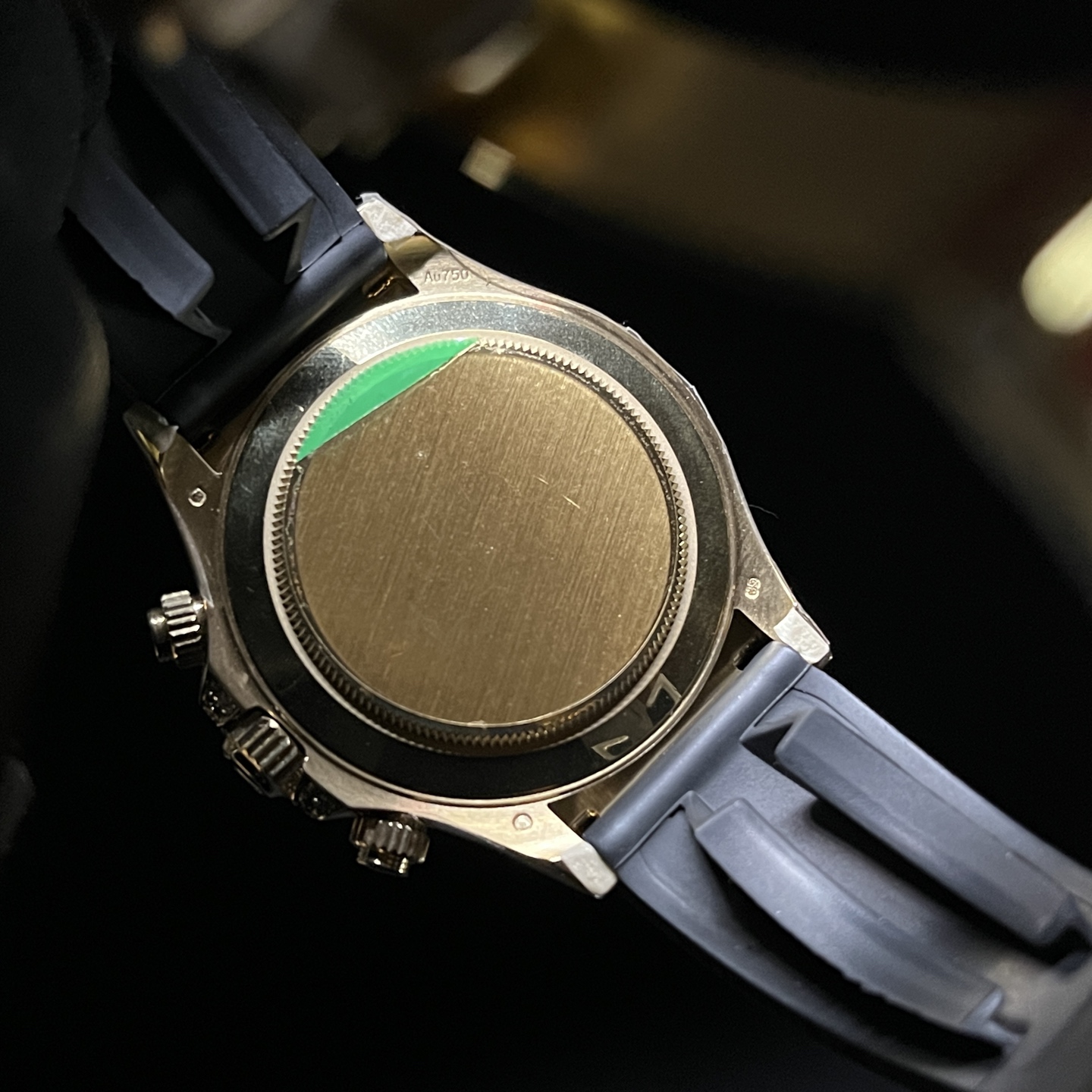 Back view of luxury gold chronograph watch with polished caseback, Au750 marking, and attached rubber strap