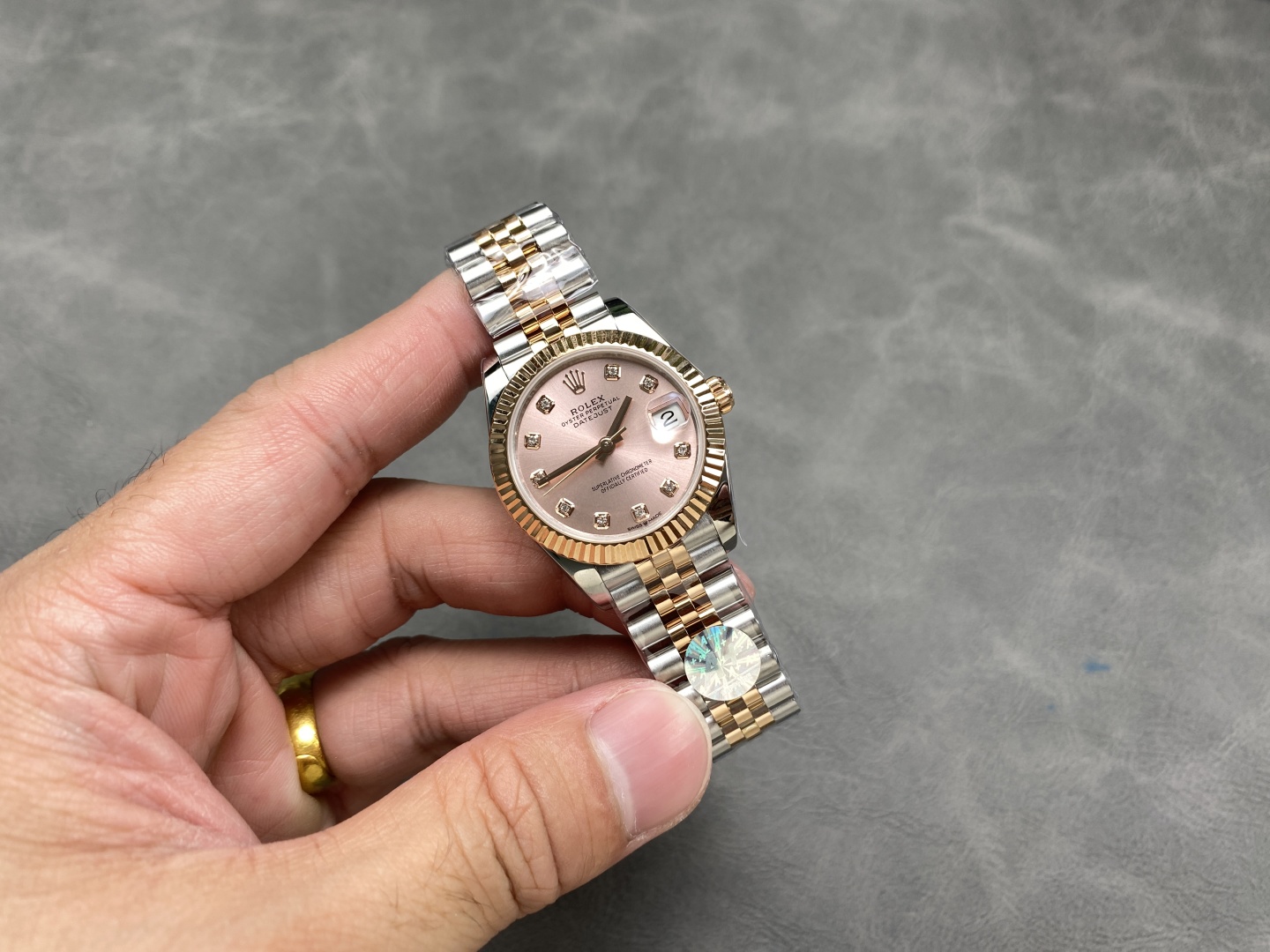 Vista en mano de un reloj clon 1:1 Rolex Datejust de dos tonos, mostrando el brazalete y la caja.