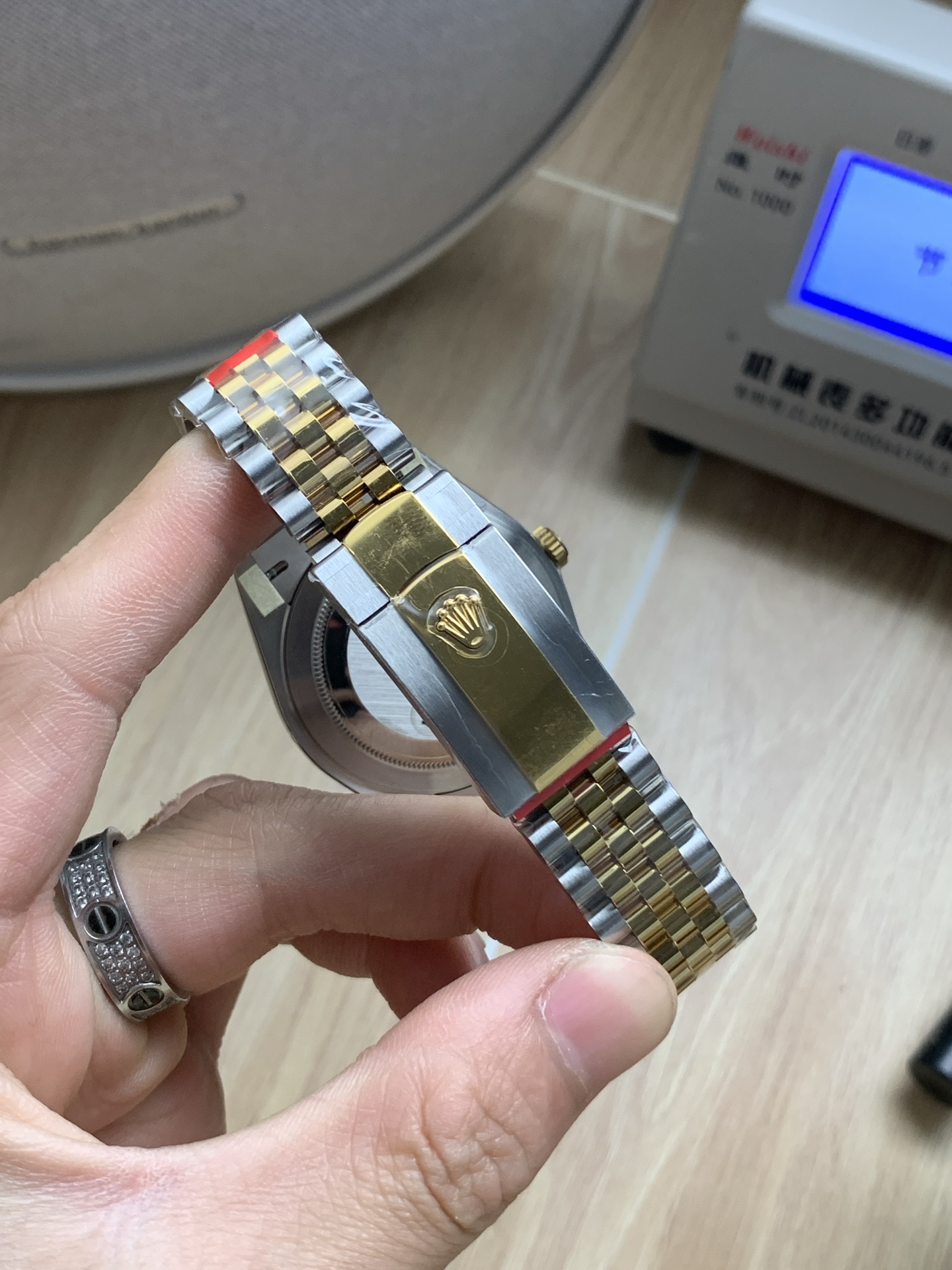 Close-up of the two-tone deployment clasp on a luxury Rolex Datejust replica with protective film