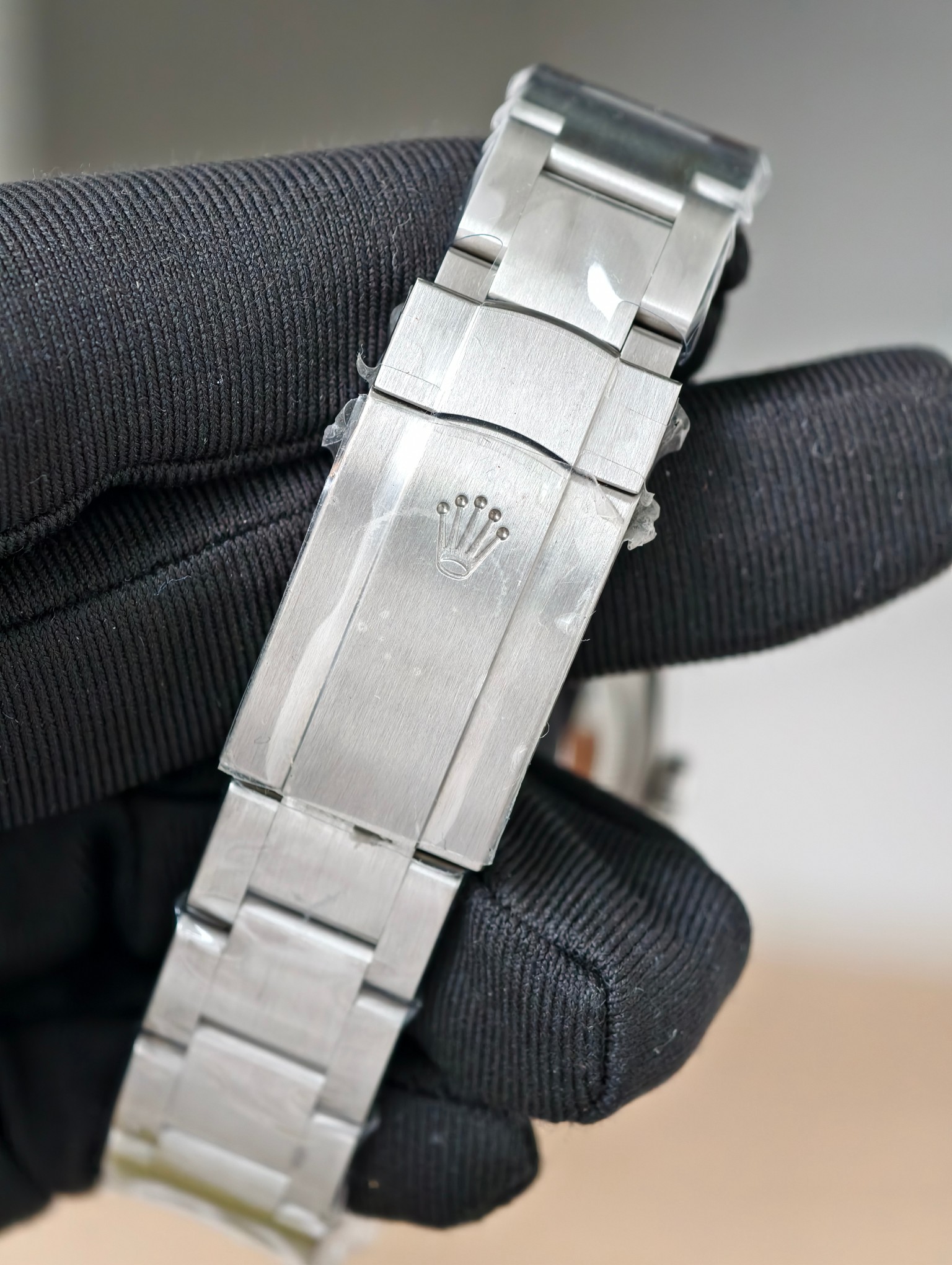 Close-up of Rolex Oyster Perpetual hidden folding clasp with engraved crown logo, double-locking system, and brushed stainless steel bracelet