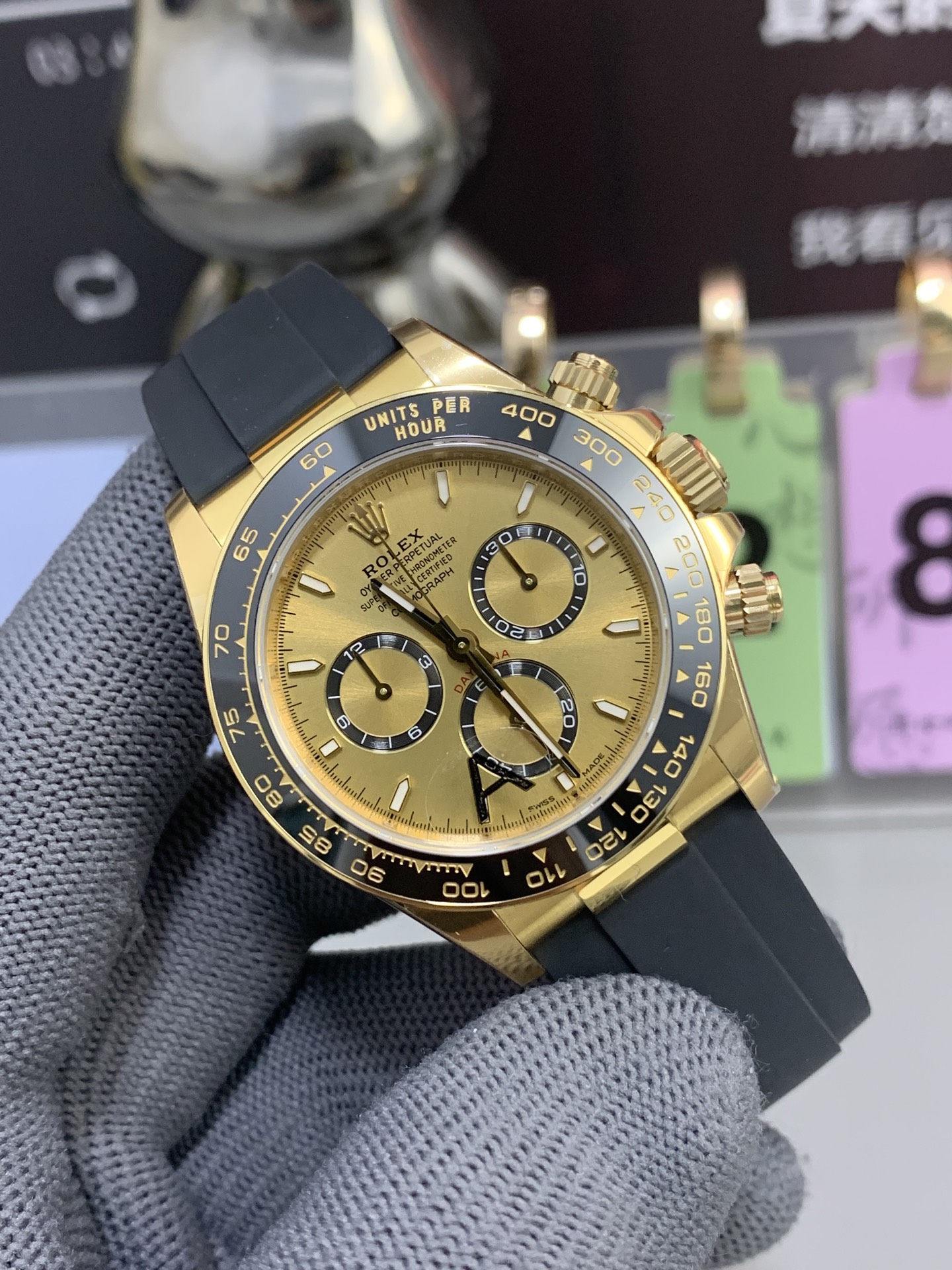 Gold-tone Daytona style rolex replica with black rubber strap and black ceramic bezel front view