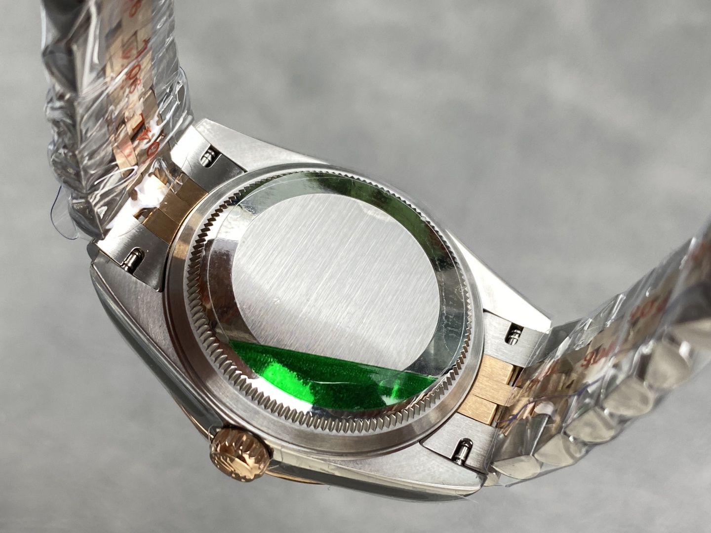 Fondo de la caja de un Rolex falso con sello verde y acabado de acero cepillado.