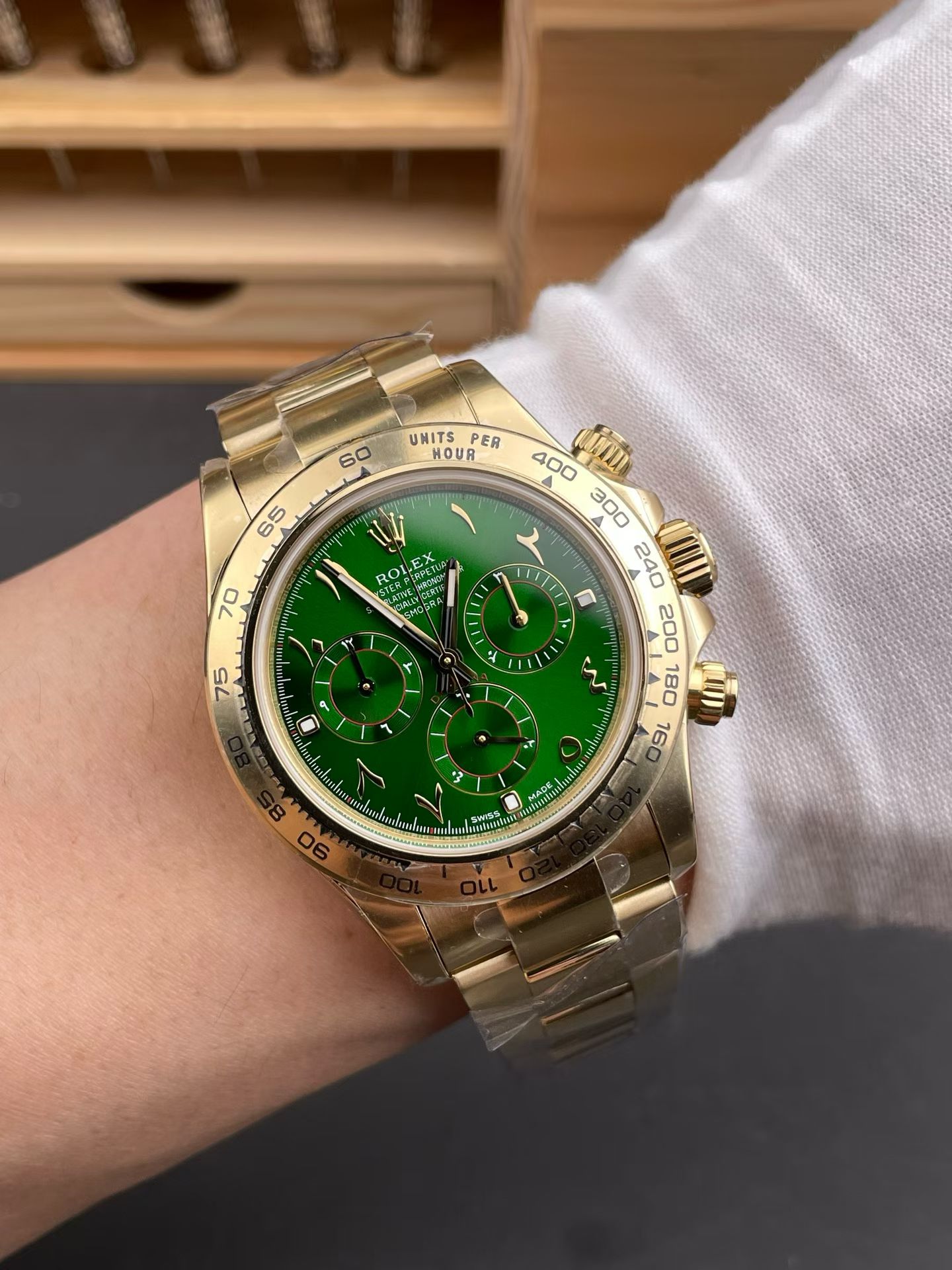 Gold Rolex Daytona replica with green dial on wrist