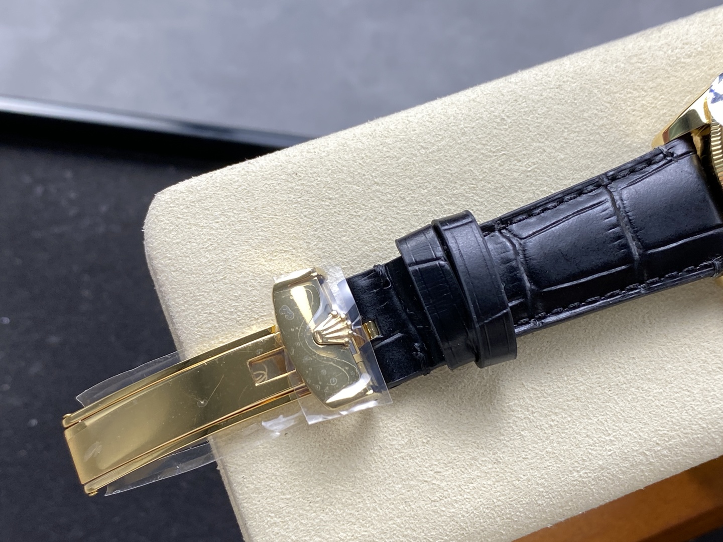 Gold clasp and black leather strap detail on a Rolex replica watch