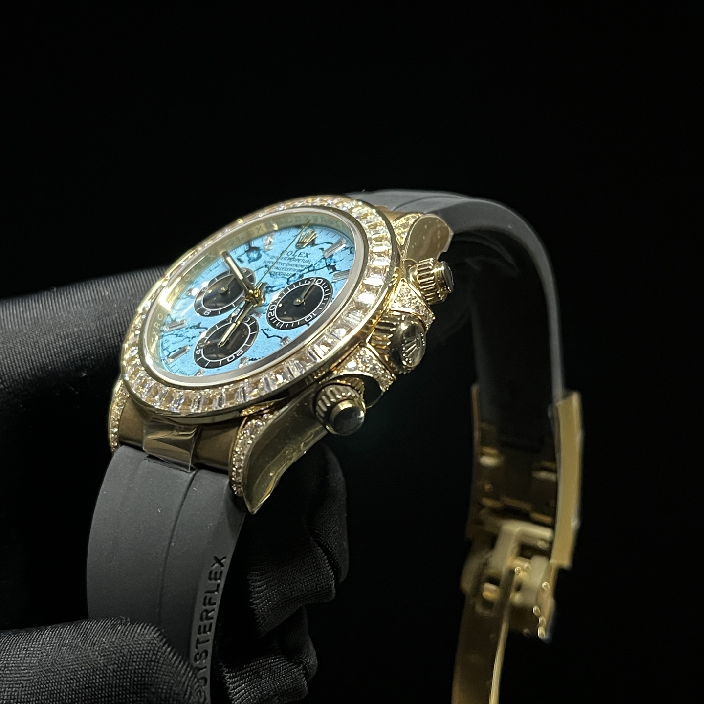 Profile view of diamond-encrusted gold Rolex Daytona super clone with chronograph pushers and rubber strap