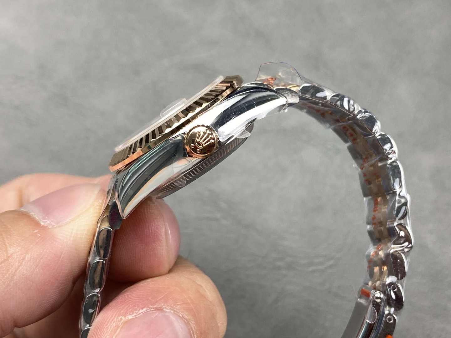 Side profile of the two-tone Datejust replica showing the slim case, rose gold crown, and integrated bracelet
