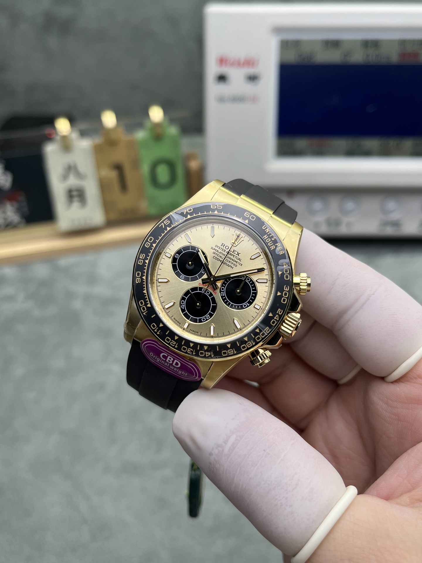 Gold dial Rolex Daytona replica with black sub-dials and rubber strap held in hand