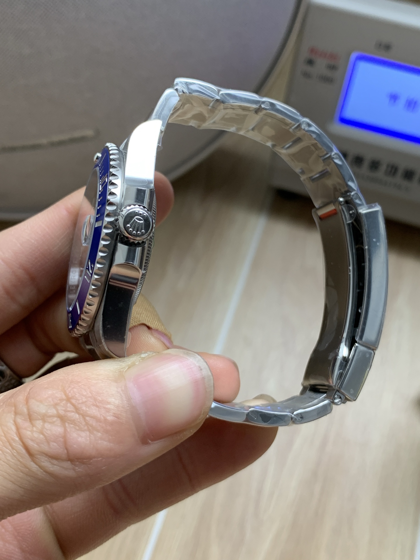 Side profile of blue bezel replica Rolex showing case thickness, crown guards, and bracelet fit