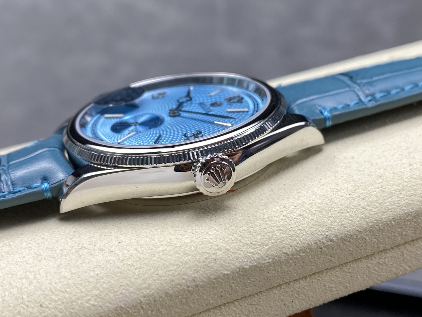 Close-up of blue guilloche dial replica timepiece with Arabic markers and small seconds subdial