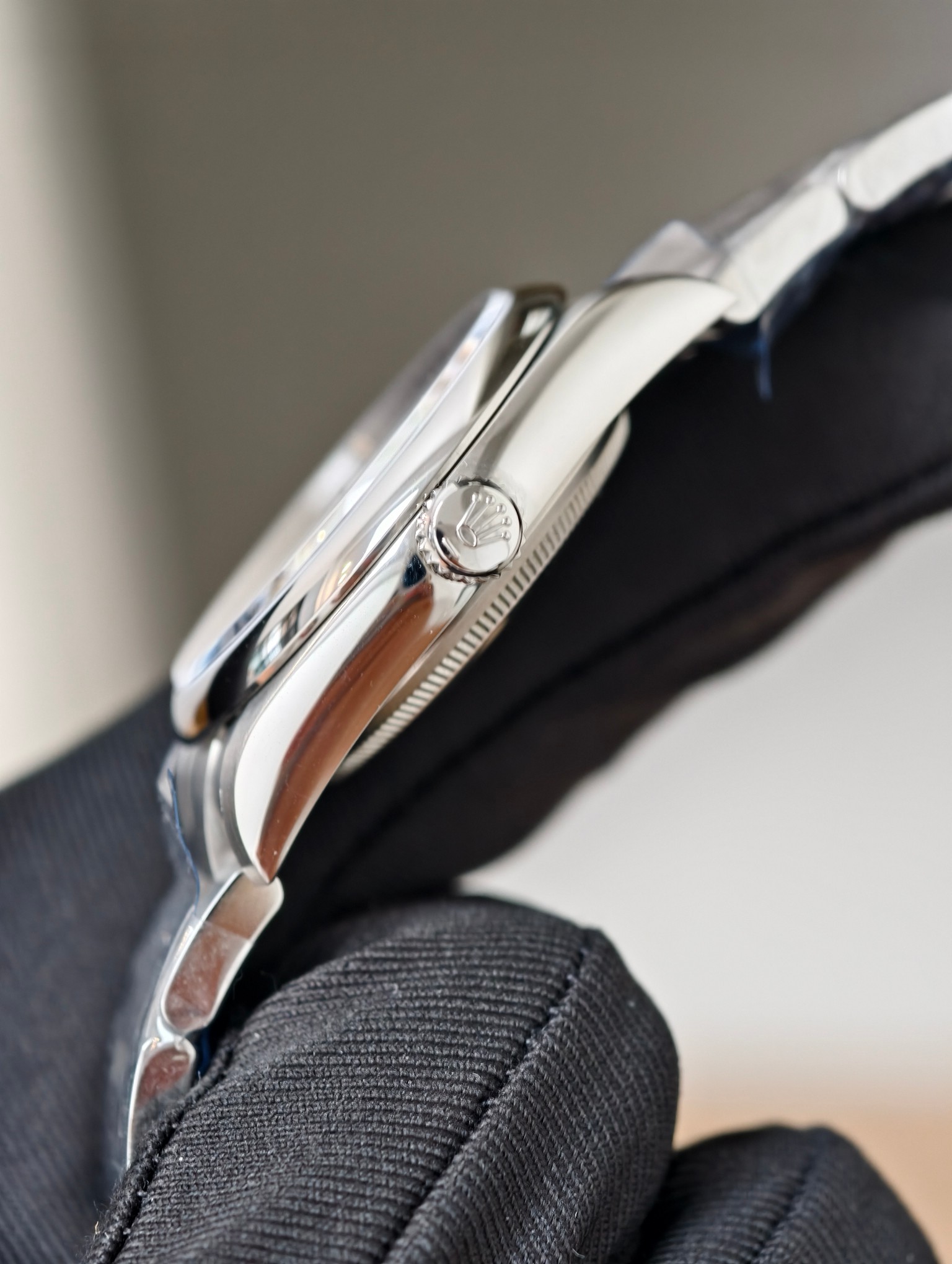 Close-up side view of Rolex replica crown and case in black glove