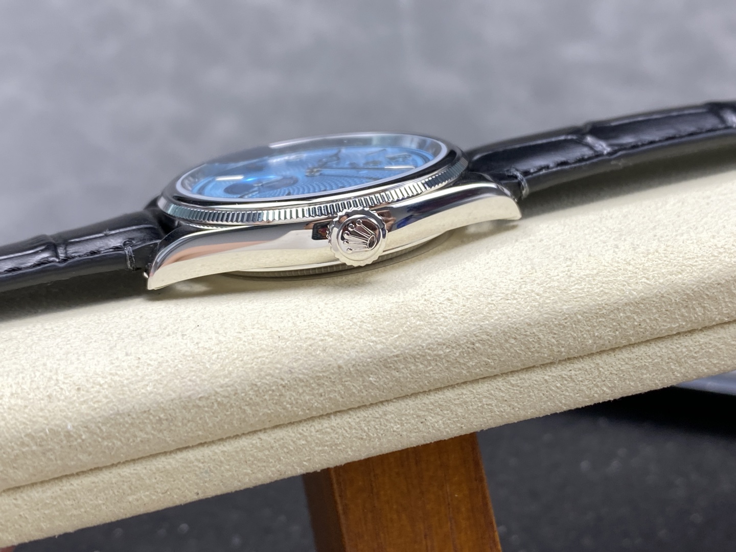Side profile of polished stainless steel case, fluted bezel, crown, and black leather strap on Rolex super clone watch