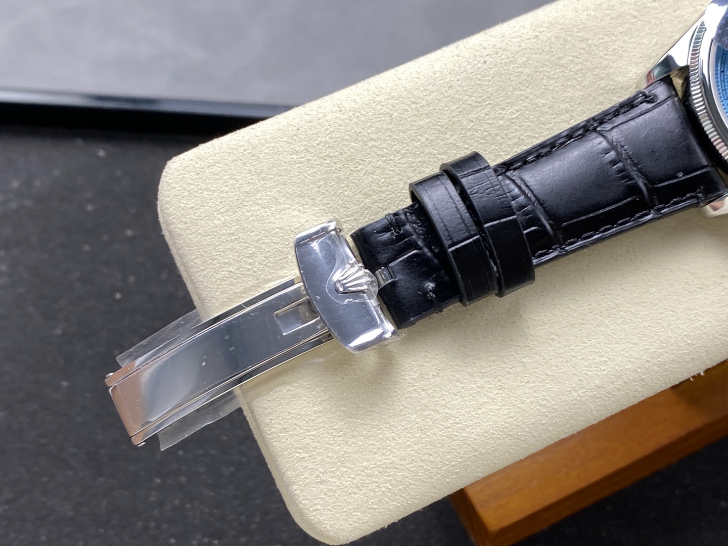 Close-up of deployment clasp with Rolex crown logo and alligator grain black leather strap on high quality replica watch