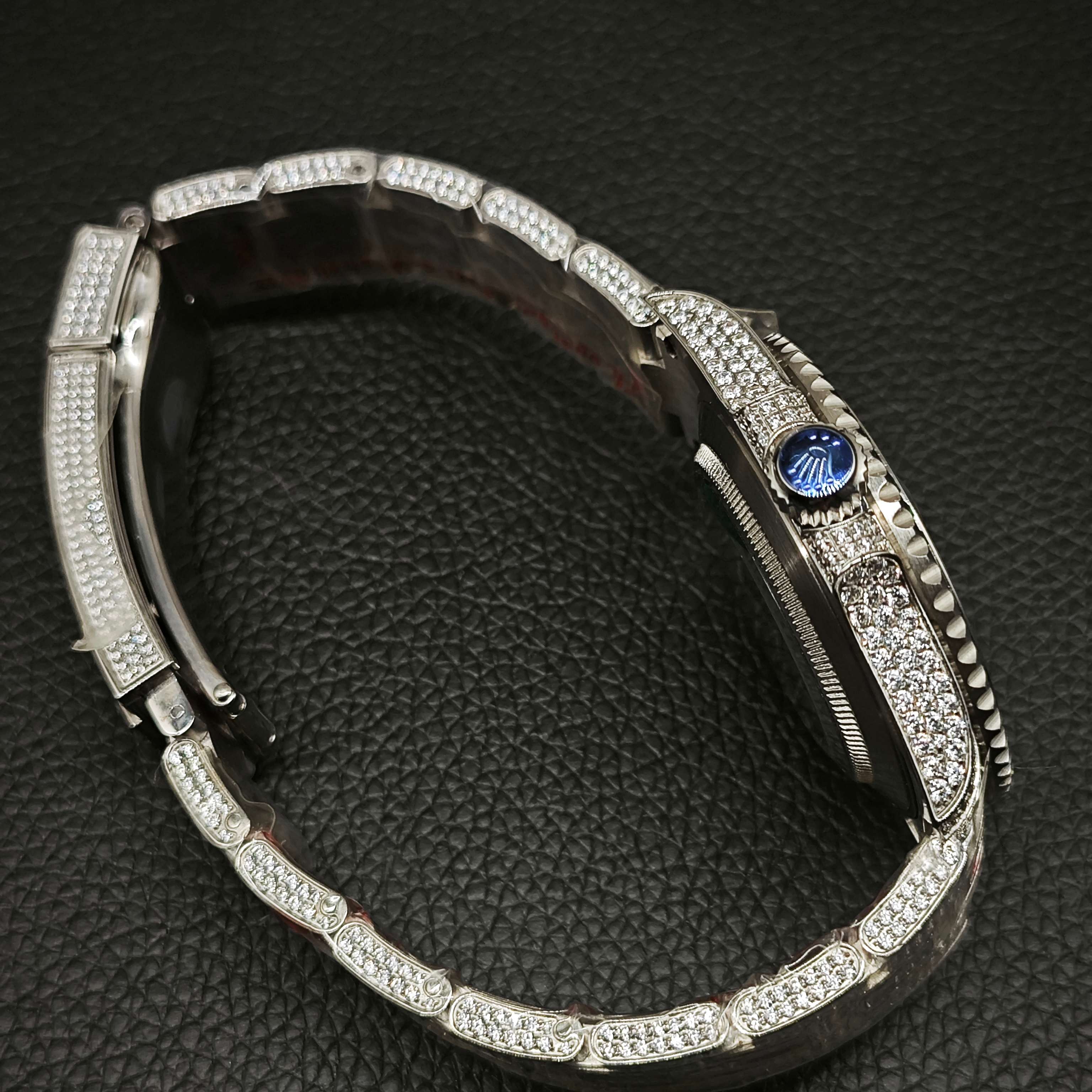 Side profile of iced Rolex super clone showing blue crown detail and stone-set case