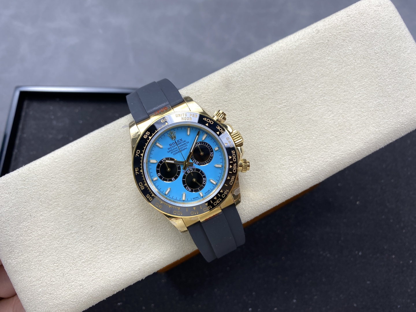 Diagonal view of high-quality gold replica watch with blue sunburst dial and precise tachymeter bezel on cream cushion