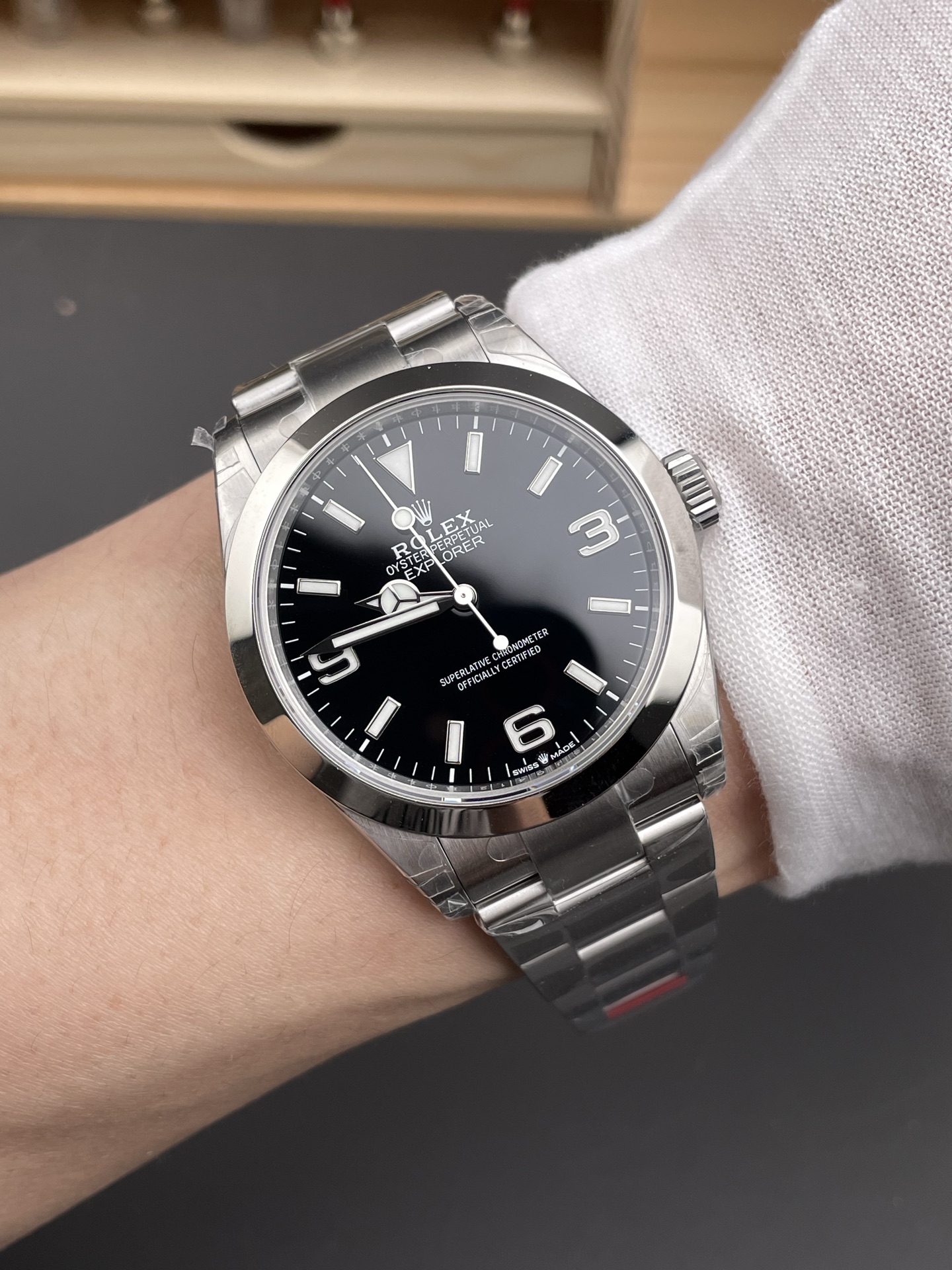 Schwarze Rolex Explorer Replik am Handgelenk mit polierter Lünette, Oyster-Band und weißem Hemdärmel