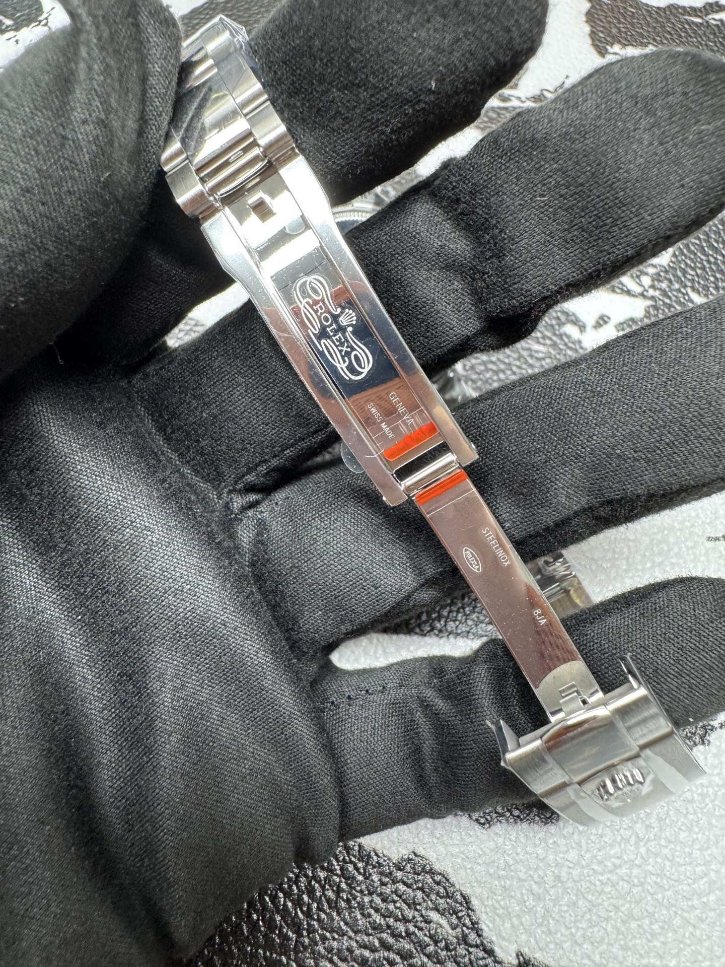Inside of the clasp showing the Rolex logo, micro-adjustment slots, and protective red stickers.