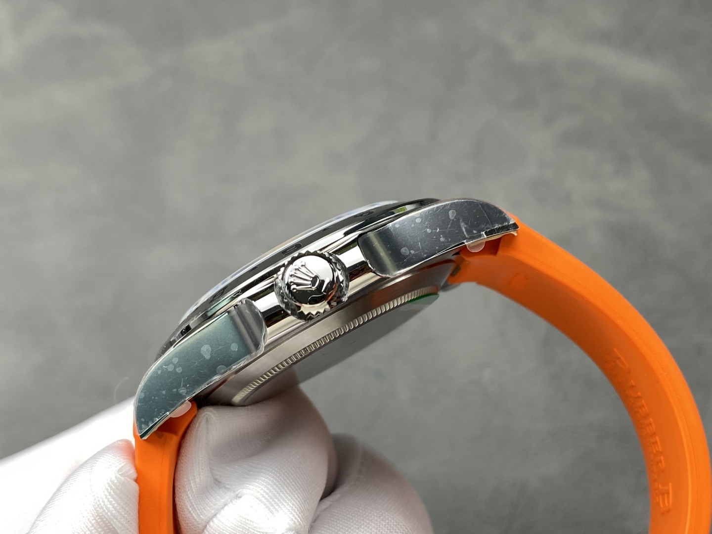 Side profile of Rolex Explorer II replica highlighting the fluted crown and polished case with orange strap