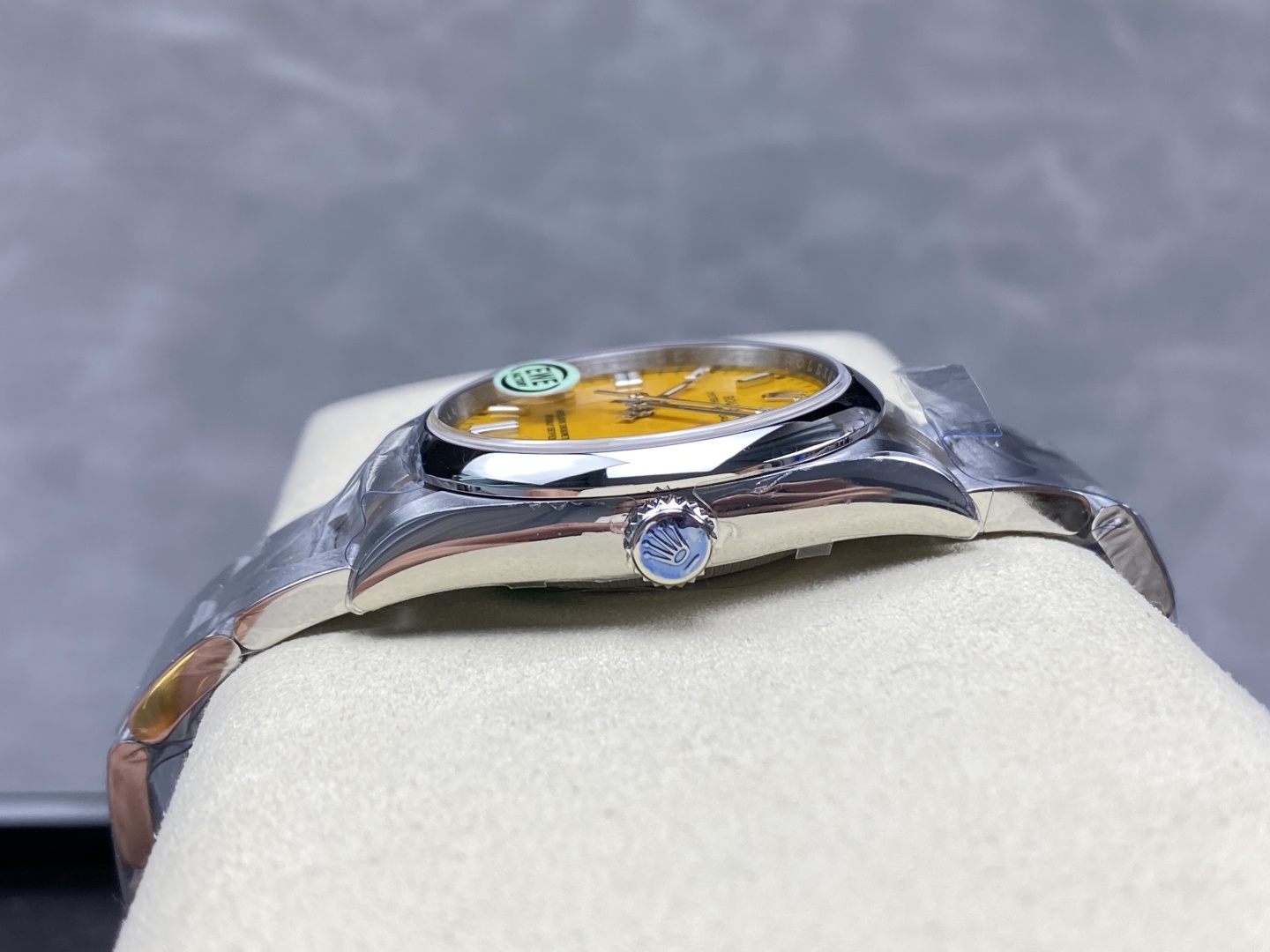Side view of the high-end replica Rolex highlighting the curved polished case, crown with blue Rolex emblem, and yellow dial through the crystal
