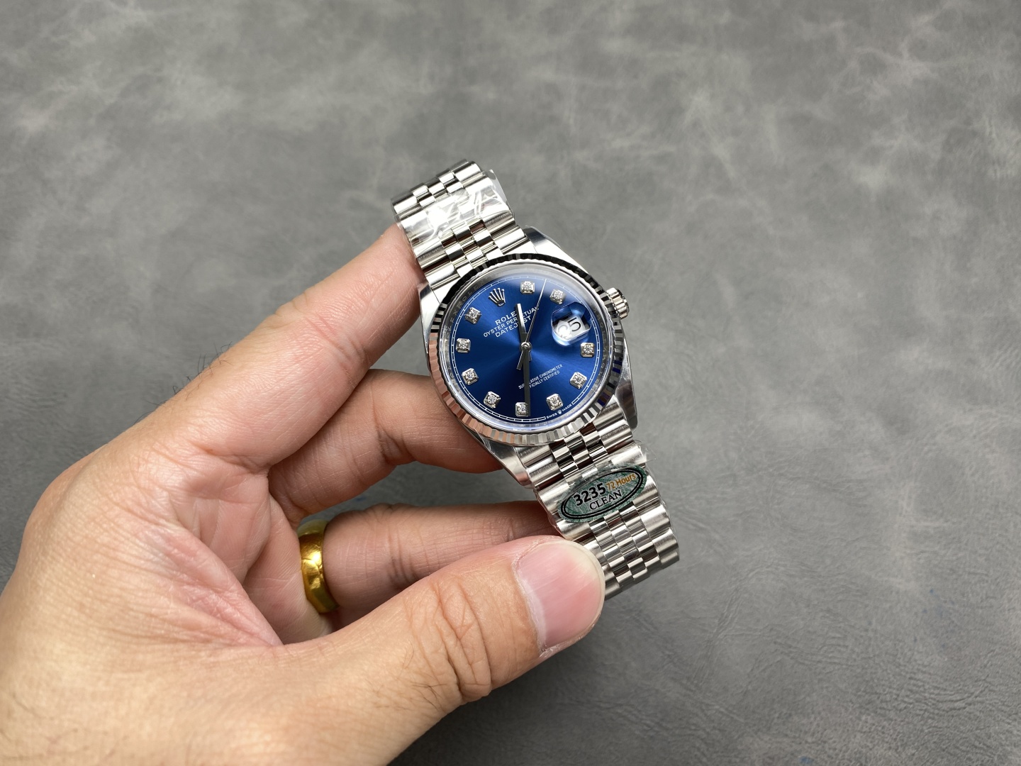 Hand holding a Clean Factory Datejust 41 replica with blue diamond dial and 3235 movement sticker