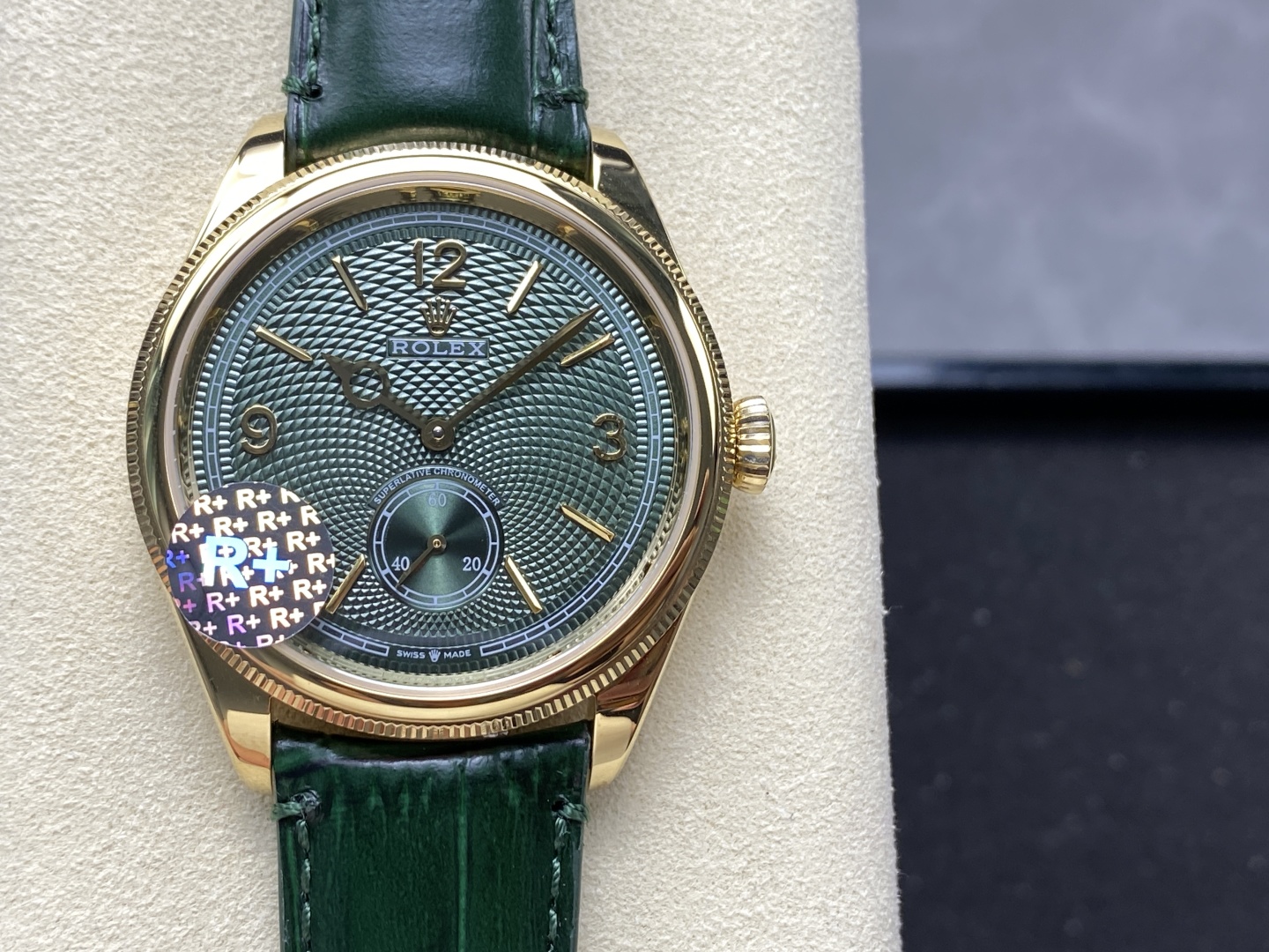 Macro detail of green wave patterned dial on gold Rolex replica with R+ authenticity sticker and gold Mercedes hands