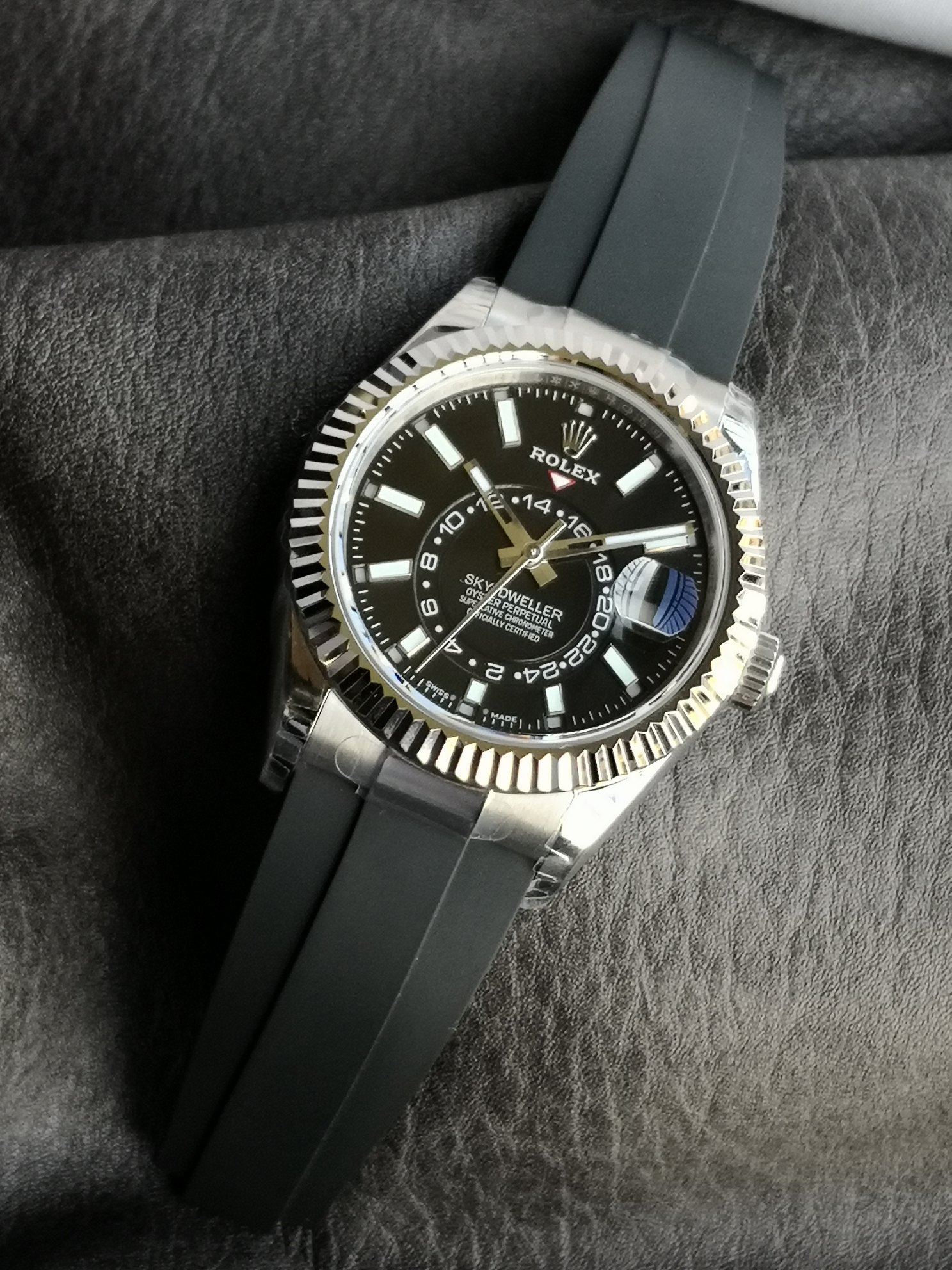 Rolex Sky-Dweller replica watch with black dial and gold fluted bezel on a rubber strap