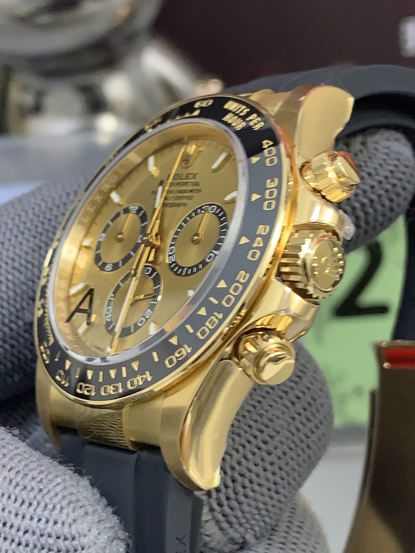 Three-quarter side profile of gold-tone rolex copy watch with black rubber strap and polished case