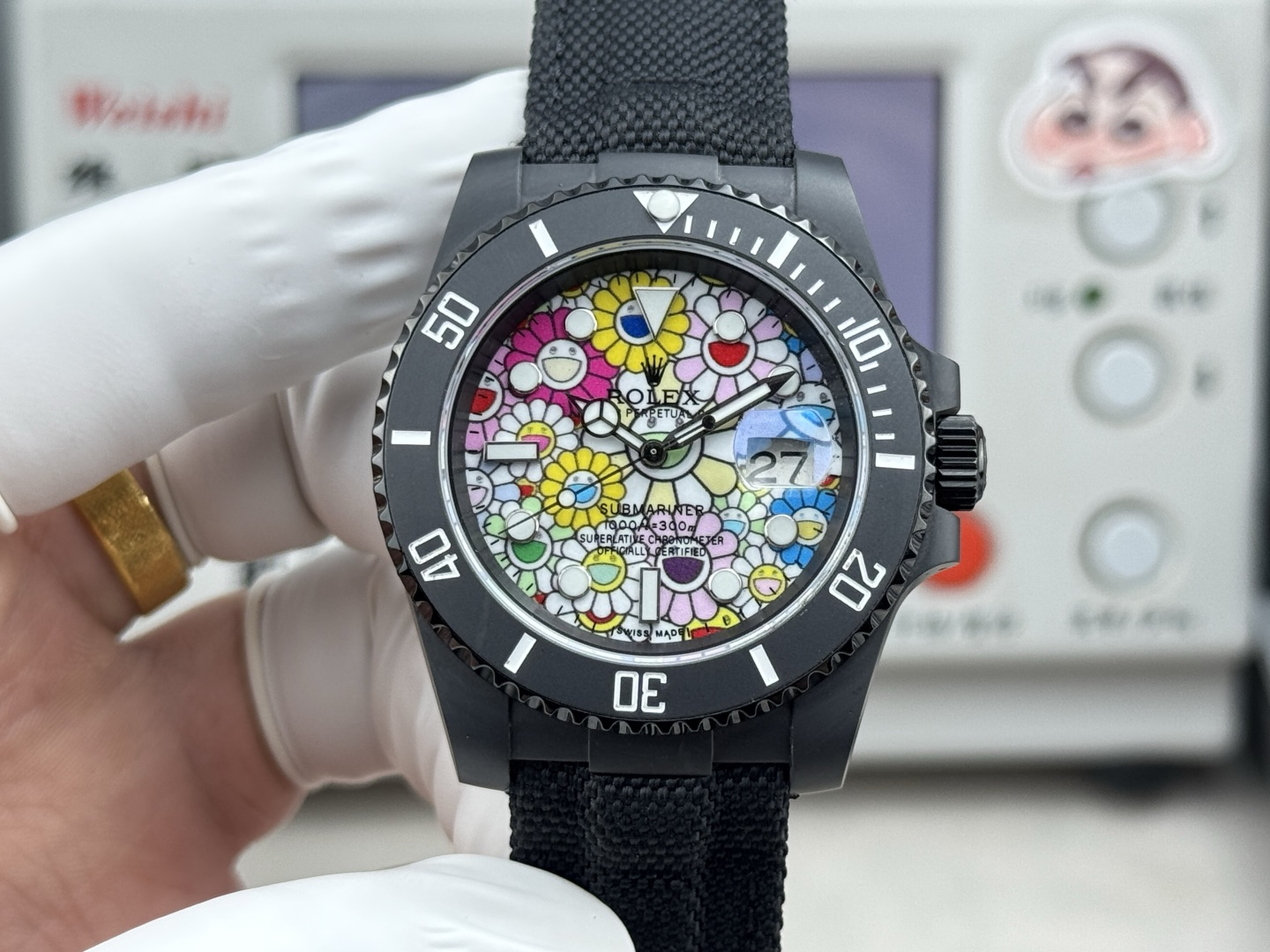 Close-up front view of the black DLC Submariner with multi-colored floral dial and date window at 3 o'clock.