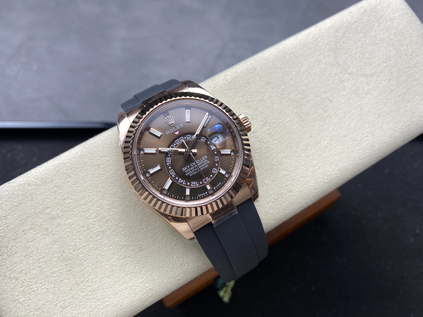 Rose gold Rolex Sky-Dweller replica watch on black rubber strap displayed on a cream watch roll