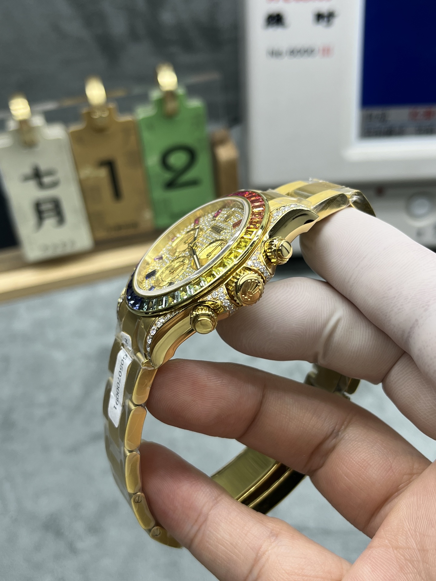 angle view of gold diamond-set rolex replica watch on hand with protective film