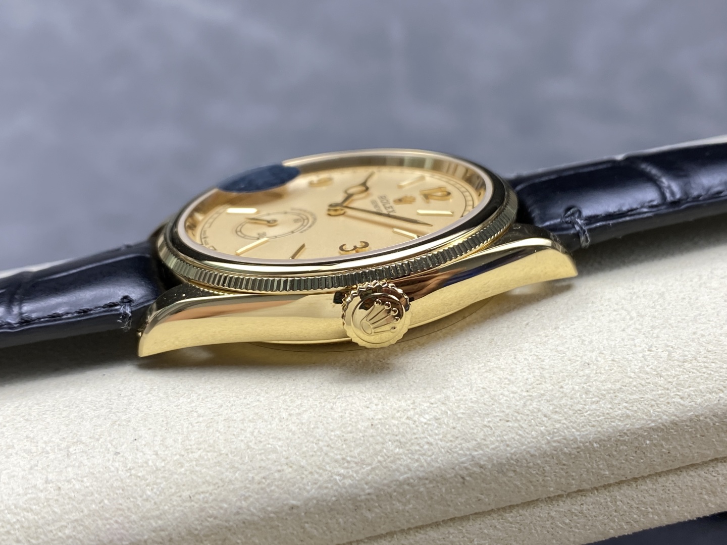 Seitenansicht der goldenen Uhr mit Krone und schwarzem Lederarmband