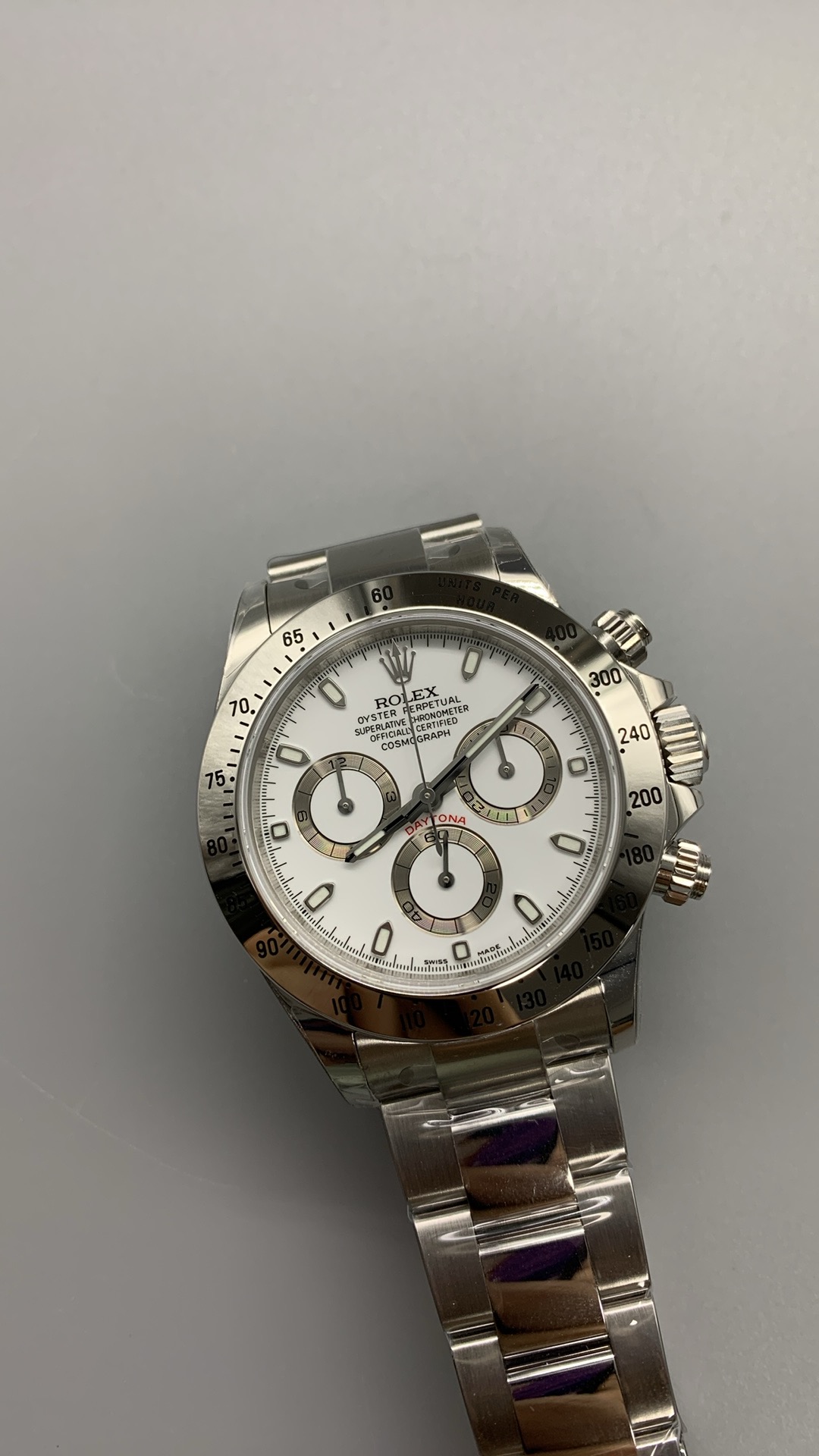 Close up of a white dial Rolex Daytona replica with stainless steel bracelet and black bezel