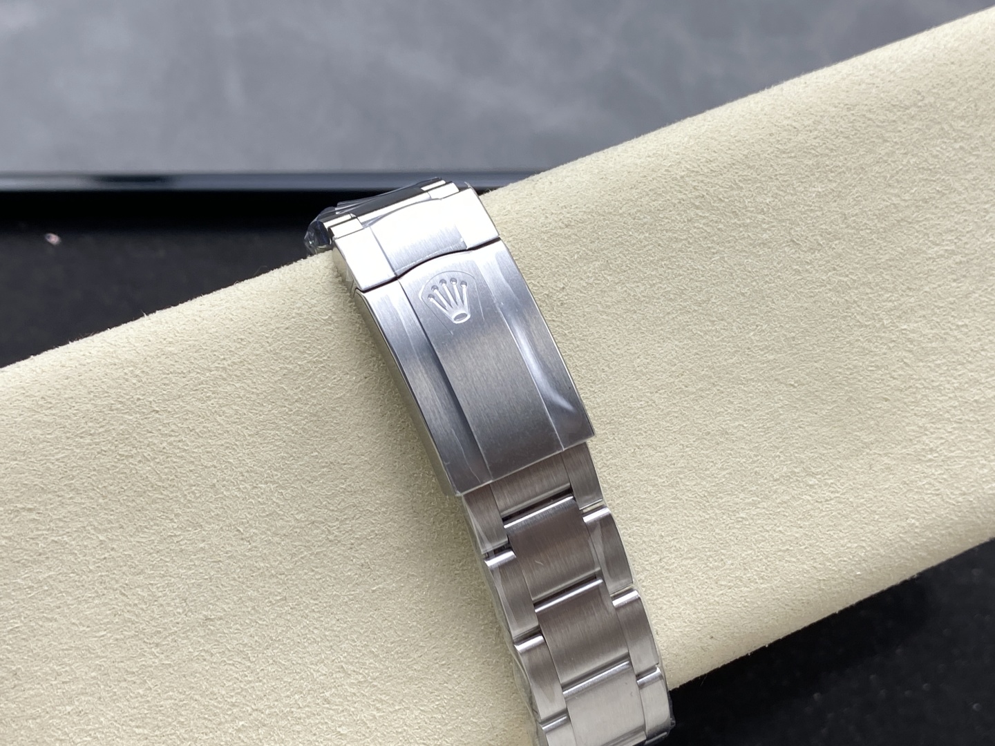 Close-up of the stainless steel deployment clasp and bracelet on the replica Rolex watch, featuring the engraved crown logo and brushed-polished finish