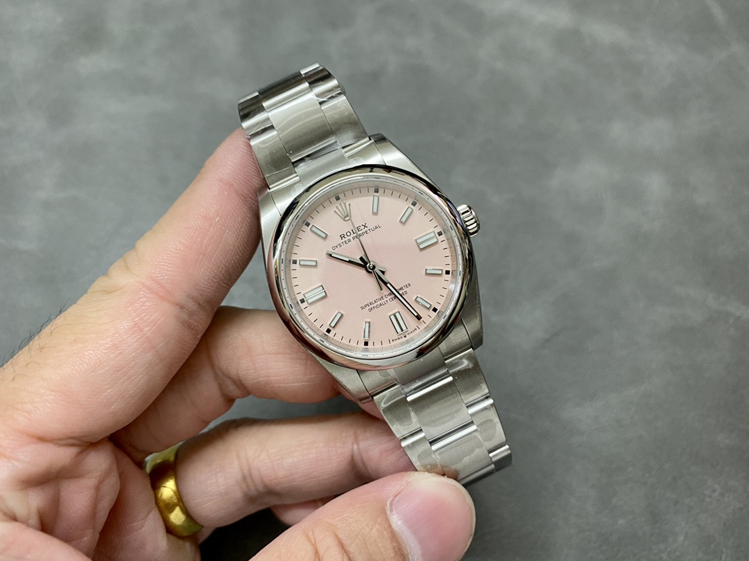 Hand holding a pink dial Rolex Oyster Perpetual super clone watch